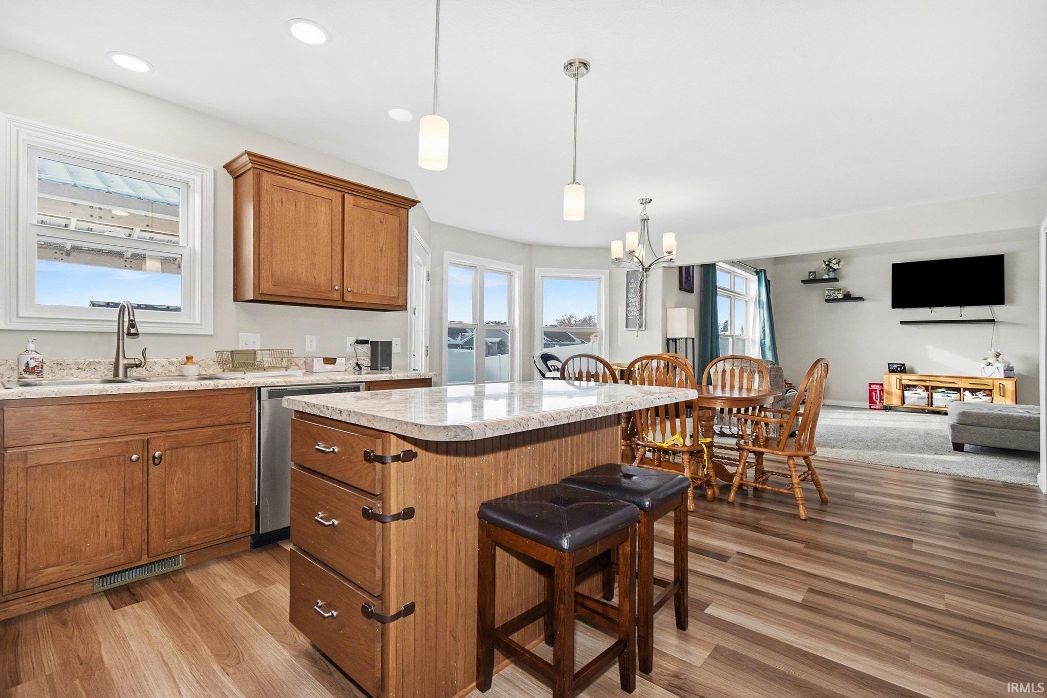 Kitchen featuring a breakfast bar, brown cabinets, decorative light fixtures, light wood-type flooring, and recessed lighting