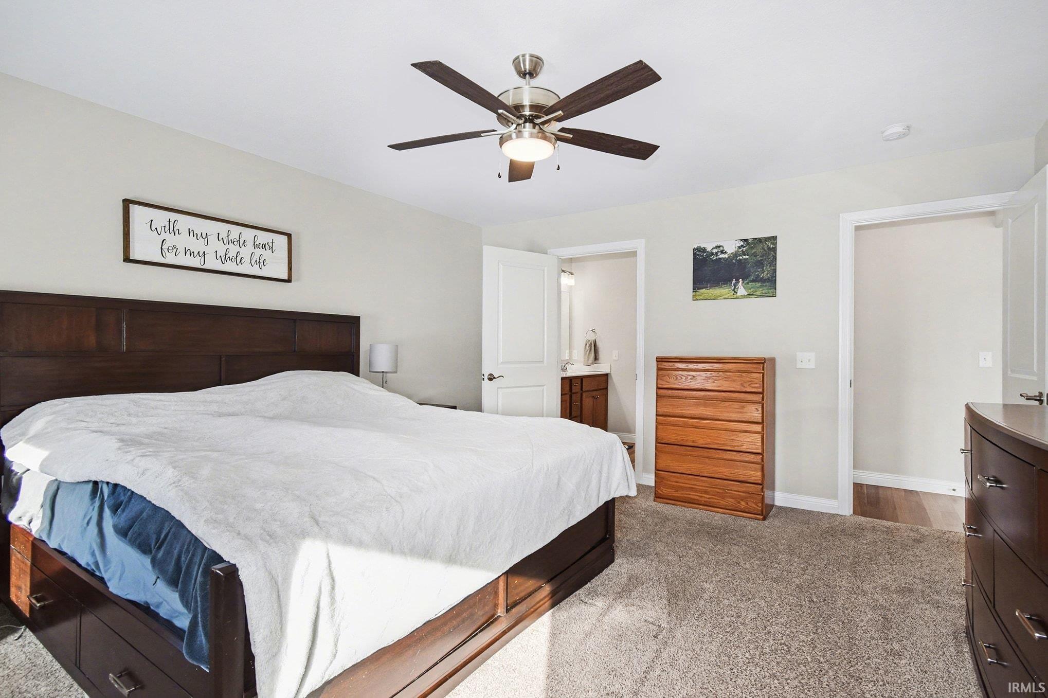 Bedroom with light carpet, a ceiling fan, and connected bathroom