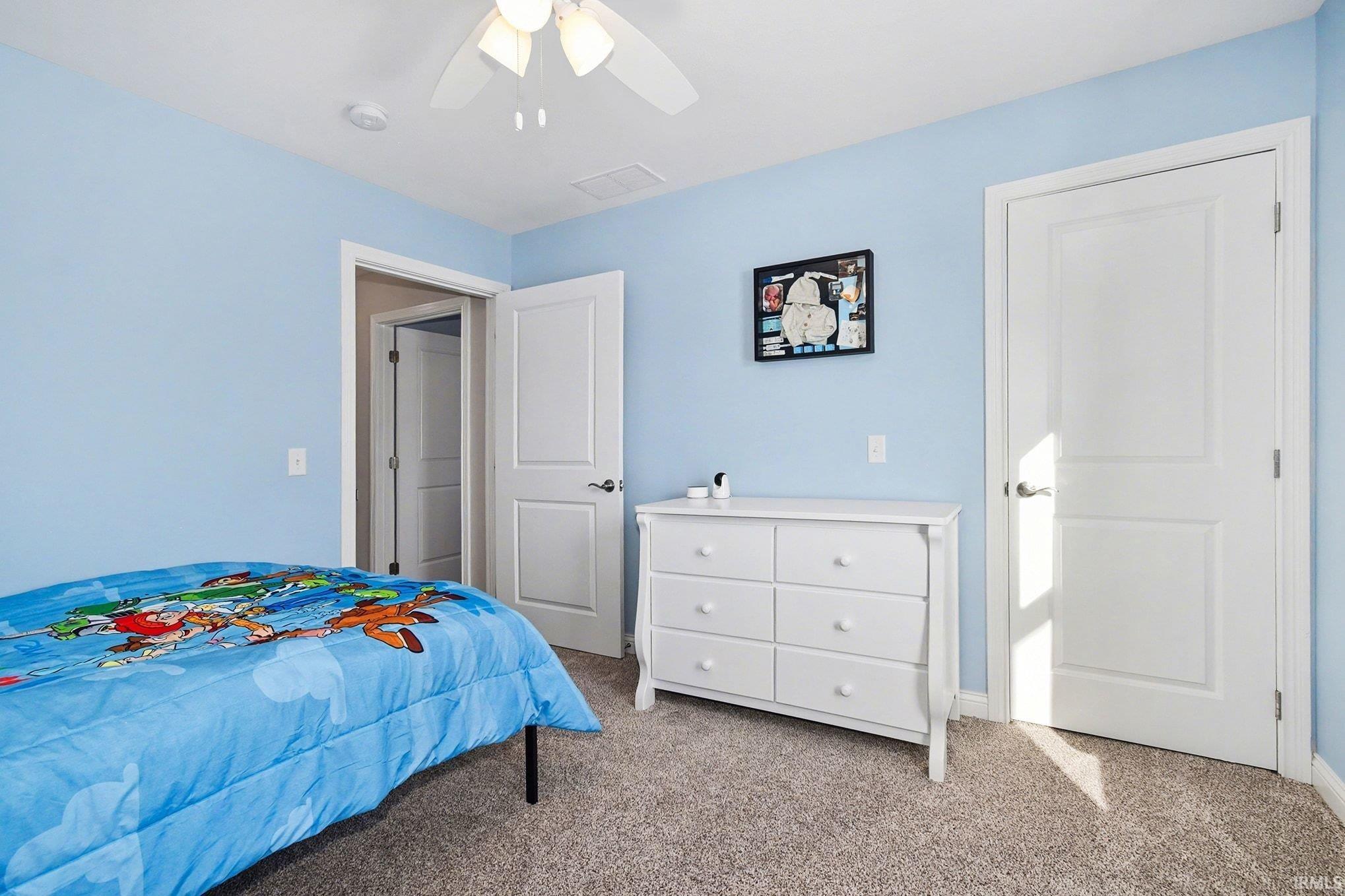 Bedroom with light carpet and a ceiling fan