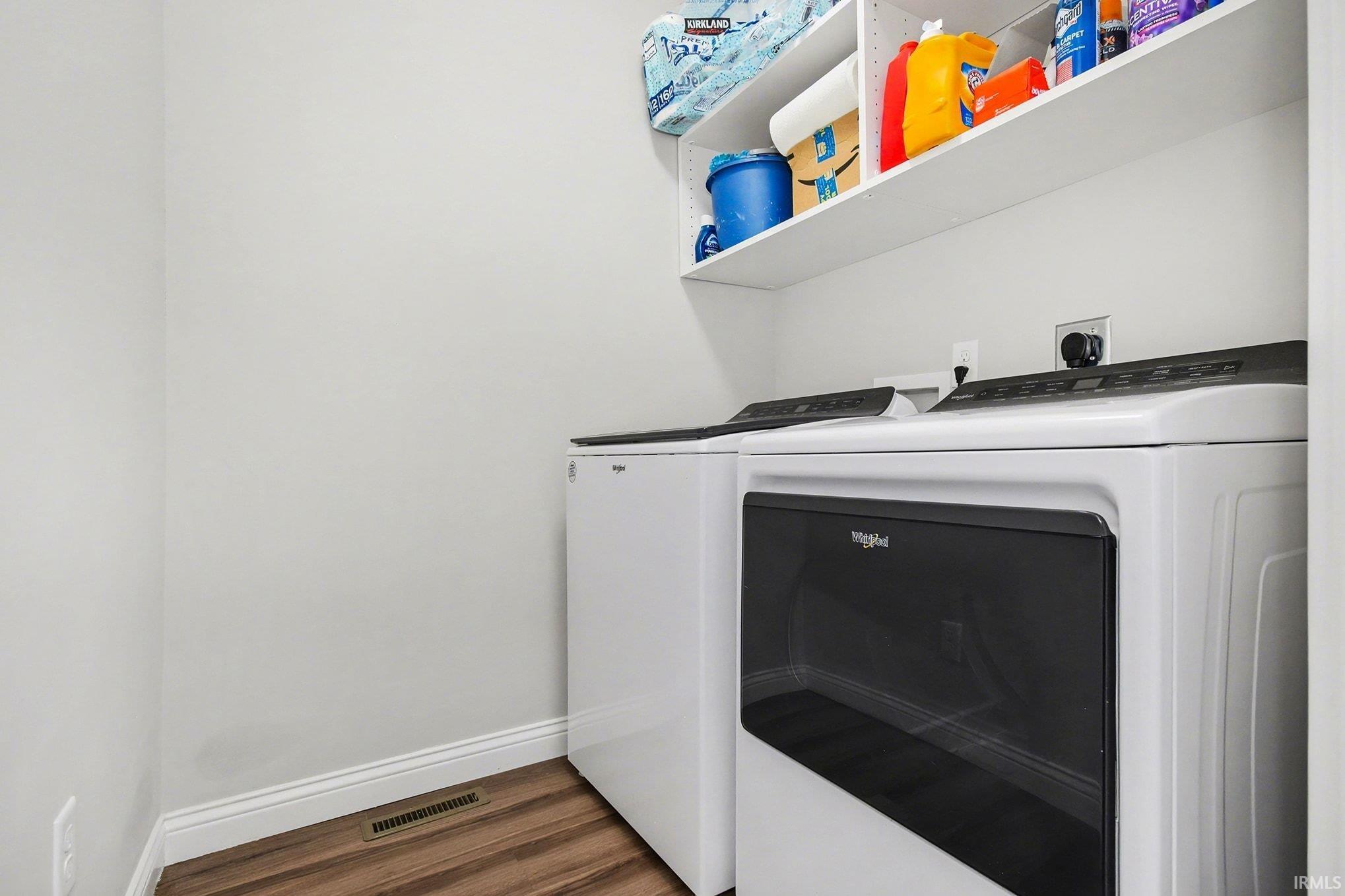Washroom with independent washer and dryer and dark wood-type flooring