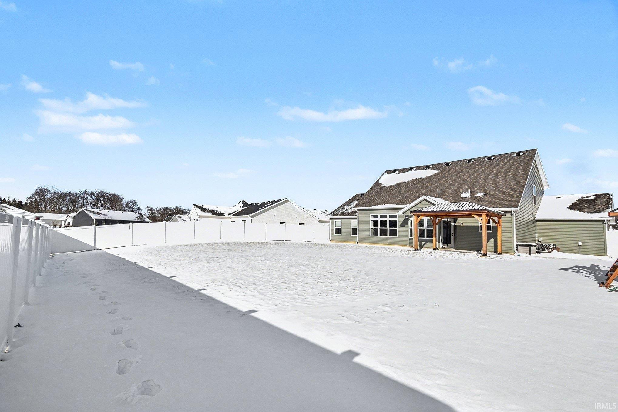 Yard layered in snow with a patio, a gazebo, a fenced backyard, and a residential view