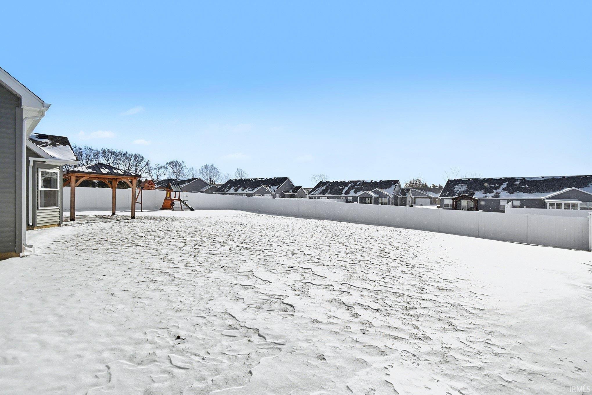 Fenced backyard featuring a residential view and a gazebo