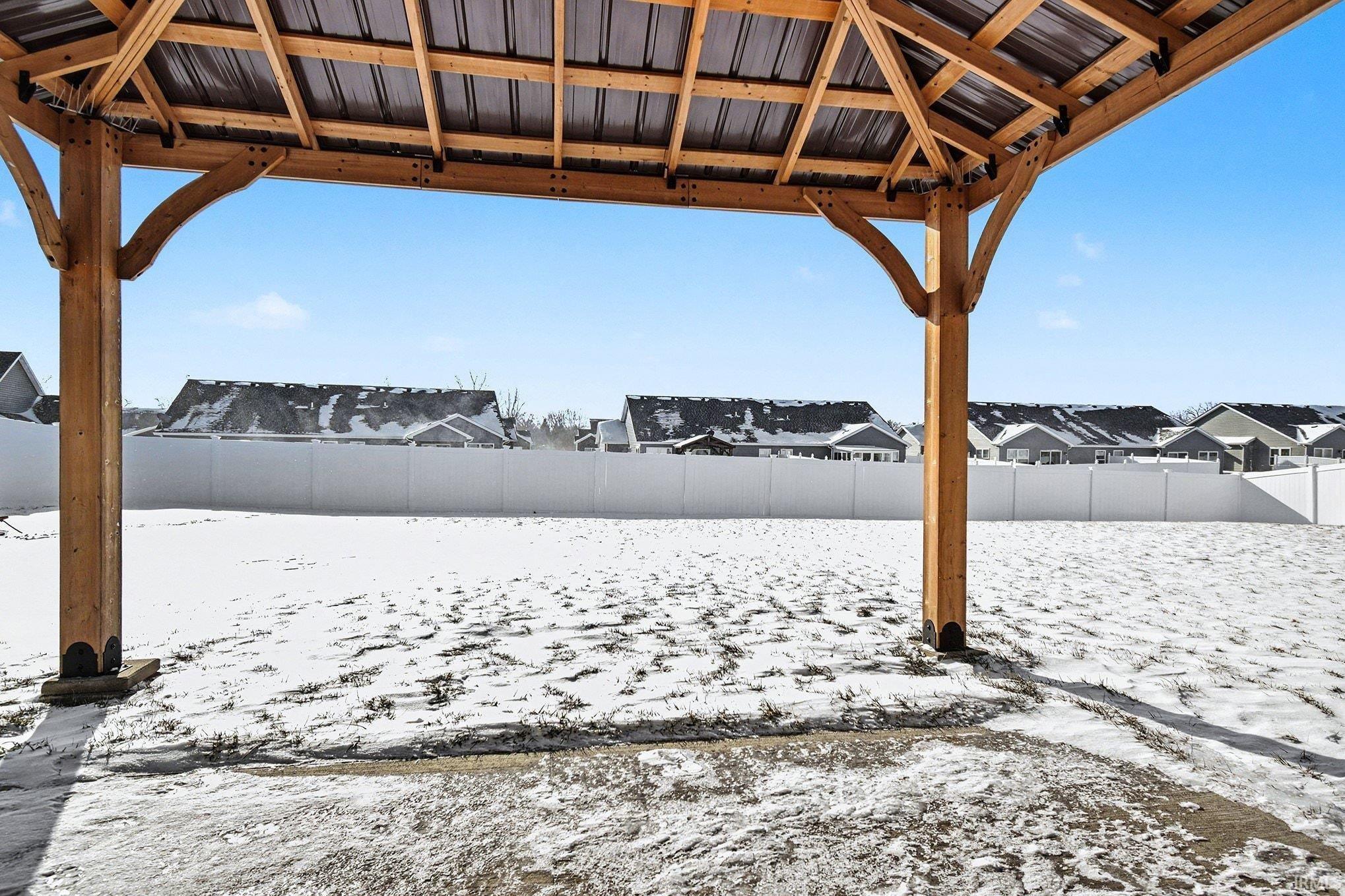 Yard layered in snow featuring a residential view, a fenced backyard, and a gazebo