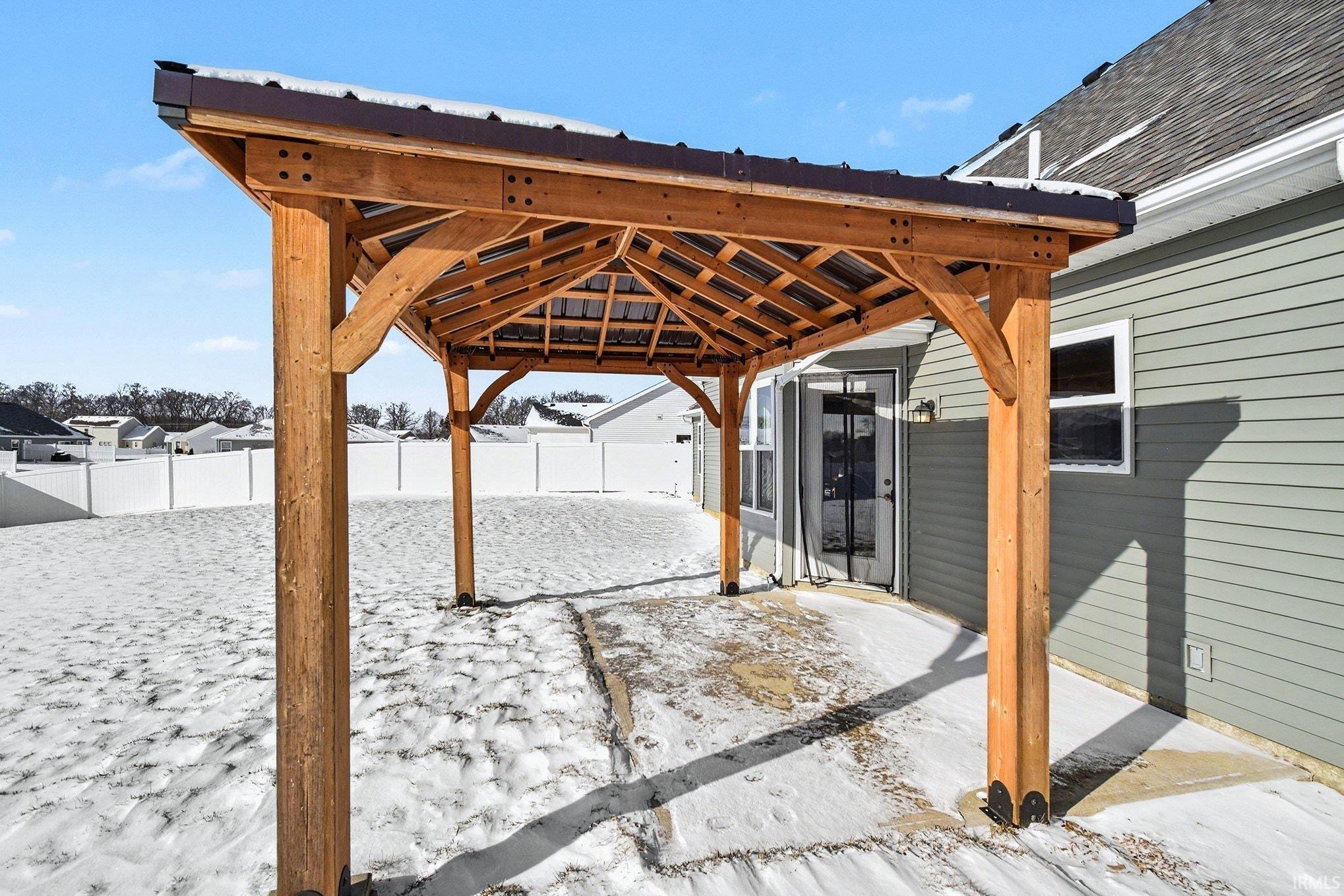 Snow covered patio featuring a gazebo, a fenced backyard, and a patio