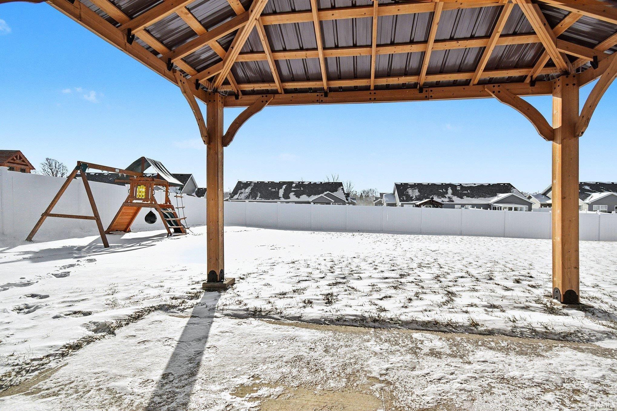 Snowy yard featuring a fenced backyard and a gazebo