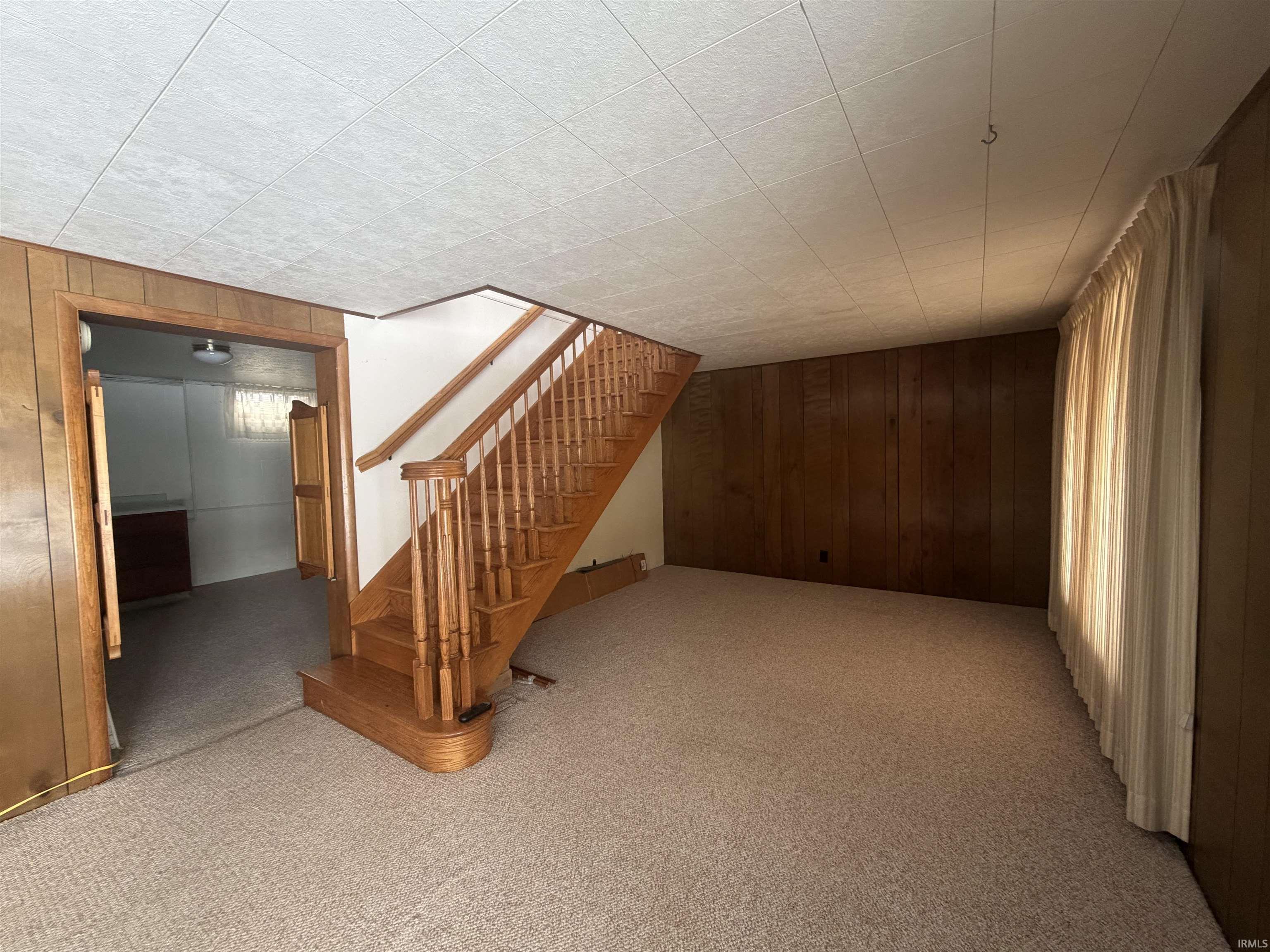 Finished basement with wooden walls, carpet, and stairs