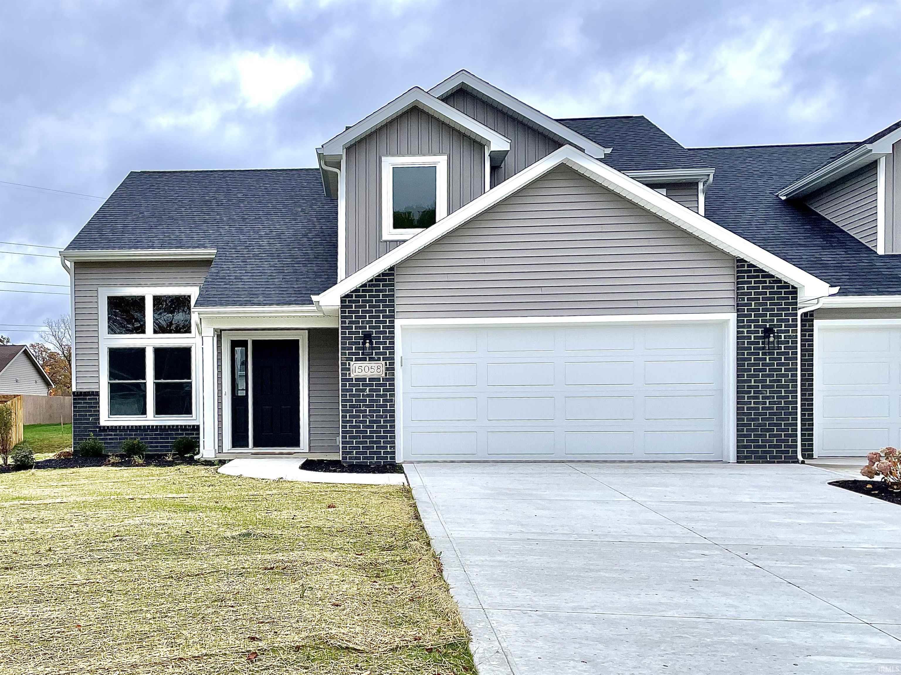 Traditional-style house featuring a shingled roof, brick siding, and concrete driveway
