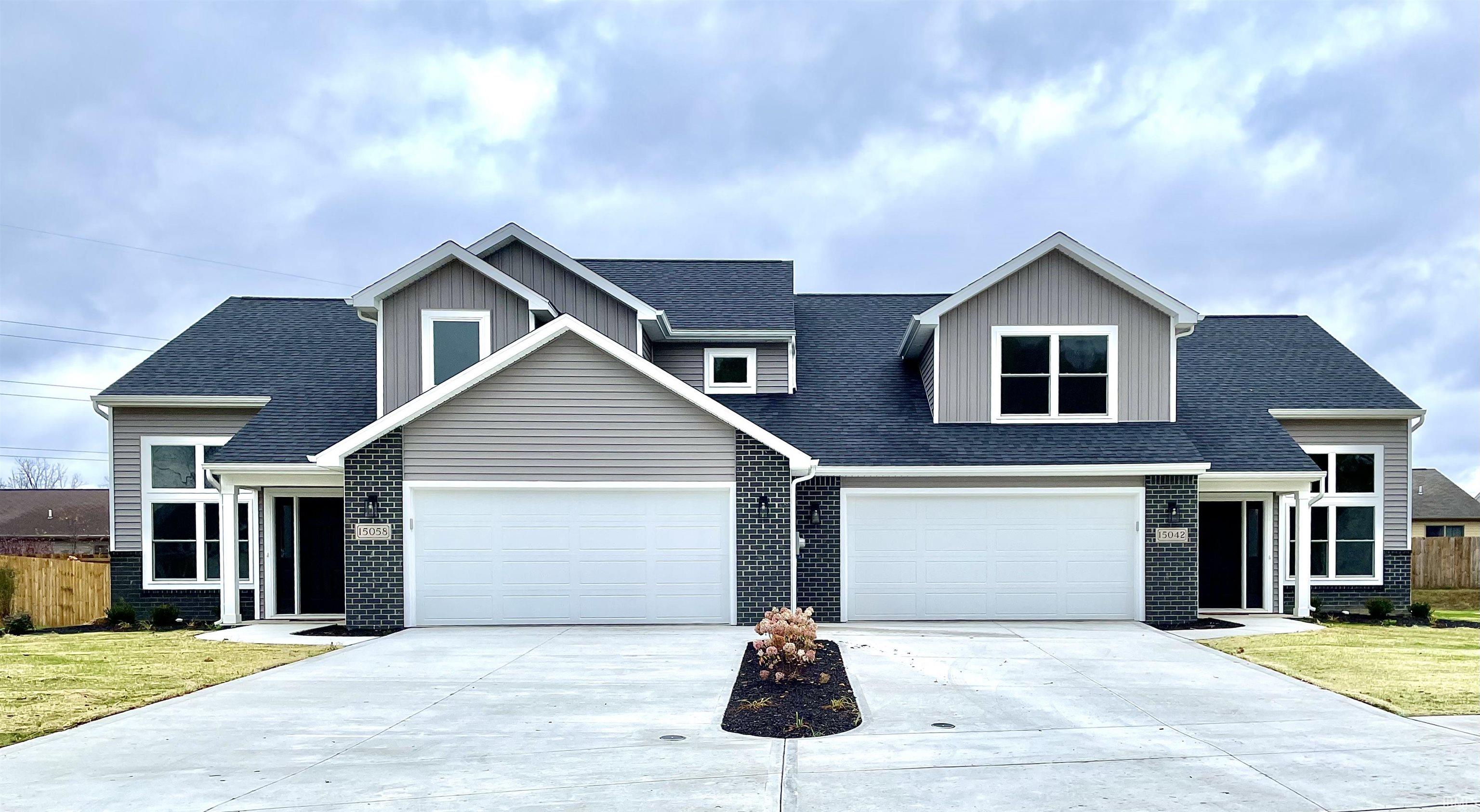 View of front facade with roof with shingles, concrete driveway, brick siding, and an attached garage