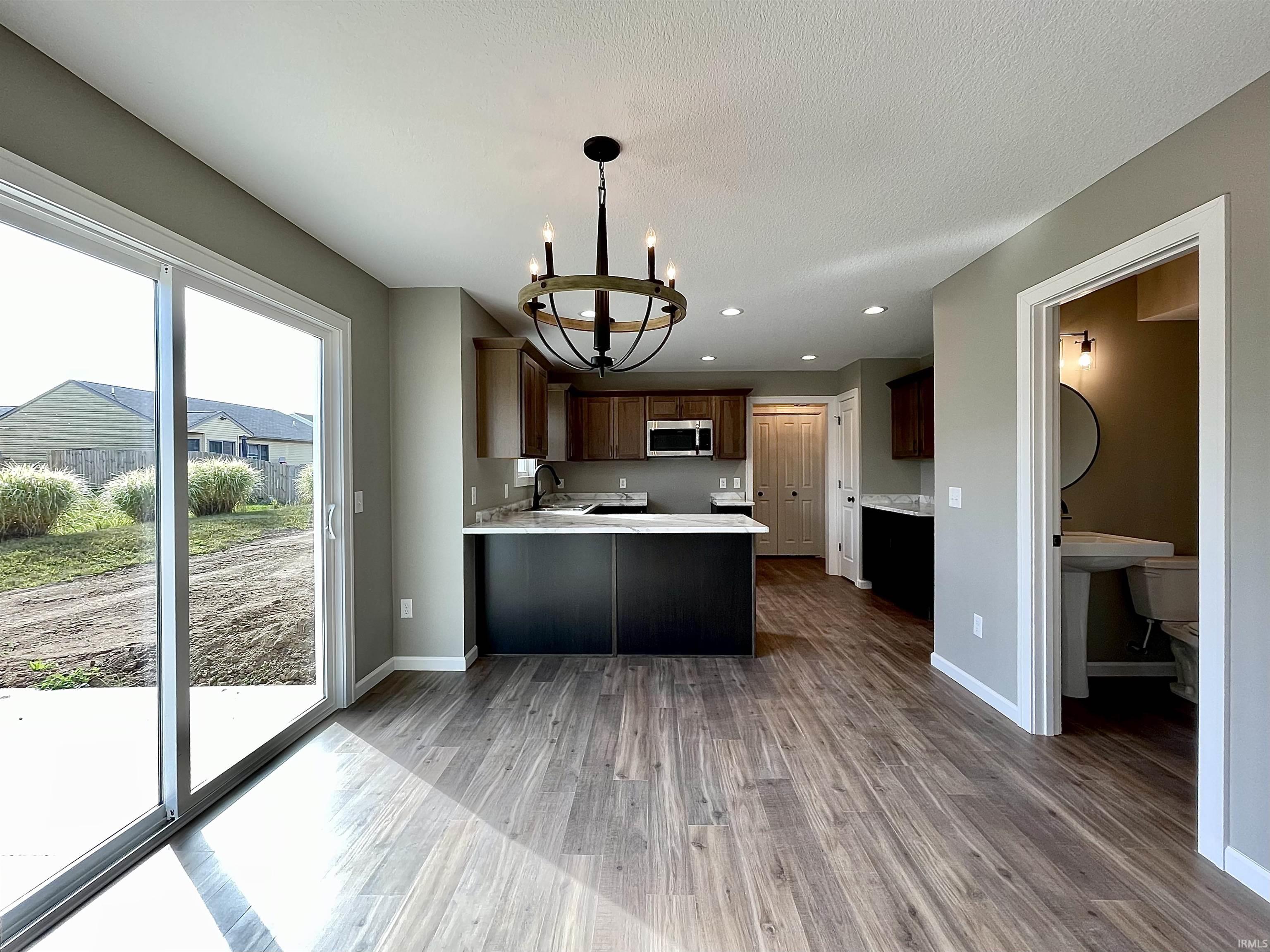 Kitchen with a peninsula, a chandelier, recessed lighting, dark wood-type flooring, and dark brown cabinets