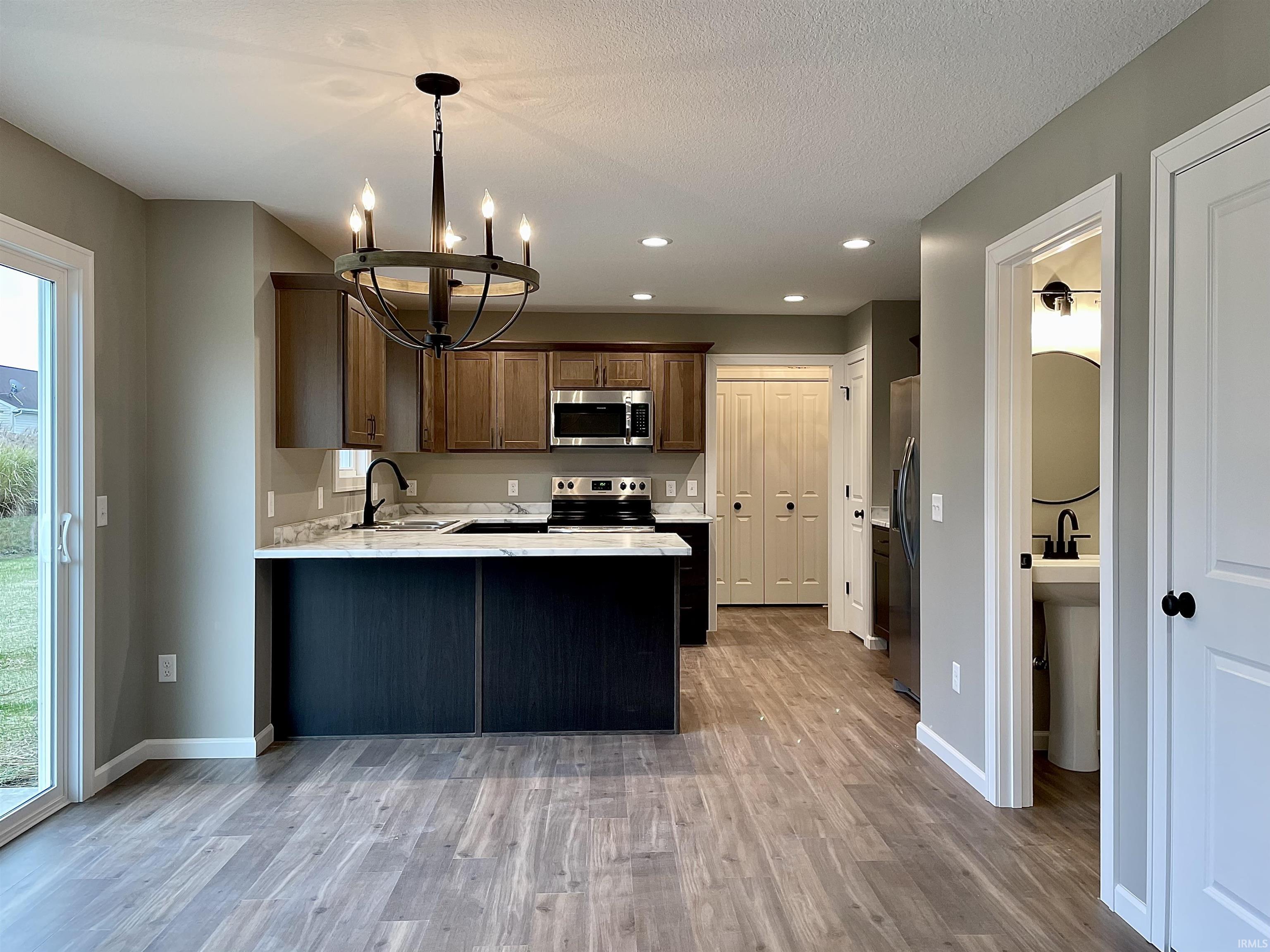 Kitchen featuring a peninsula, stainless steel appliances, pendant lighting, a chandelier, and recessed lighting