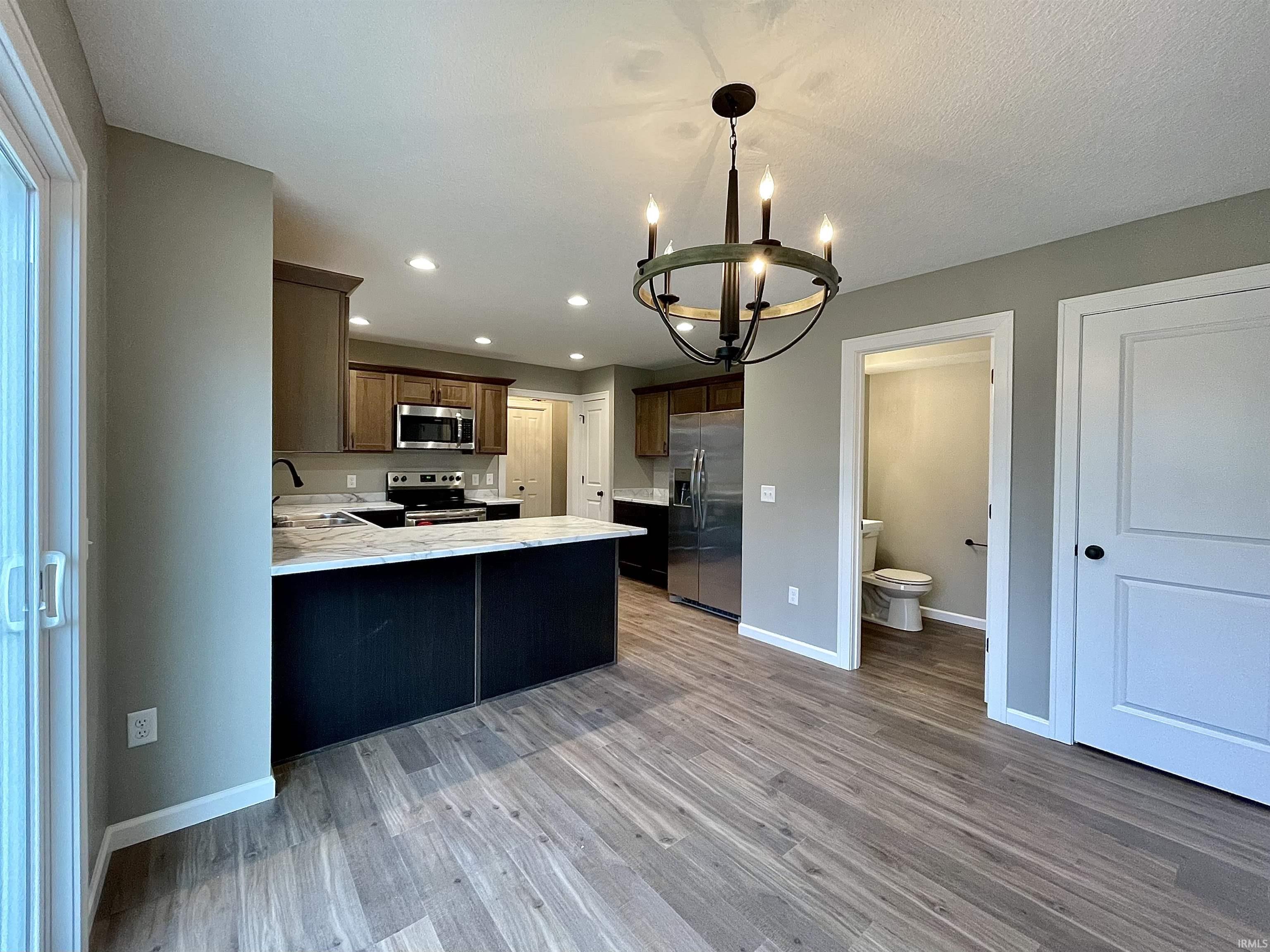 Kitchen featuring a peninsula, stainless steel appliances, hanging light fixtures, light wood-style floors, and recessed lighting