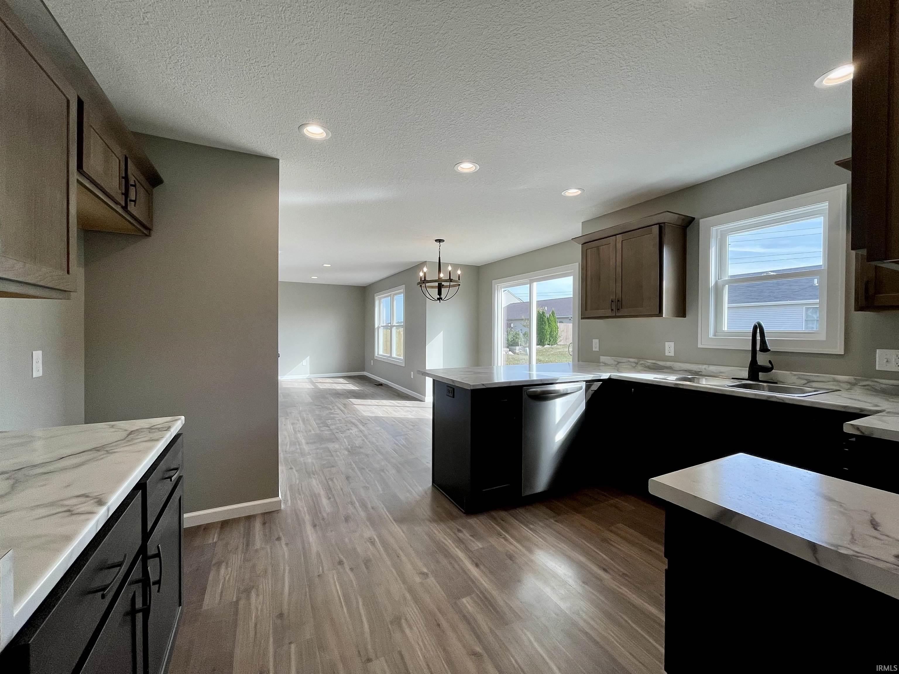 Kitchen featuring recessed lighting, light wood-type flooring, dishwasher, plenty of natural light, and a chandelier