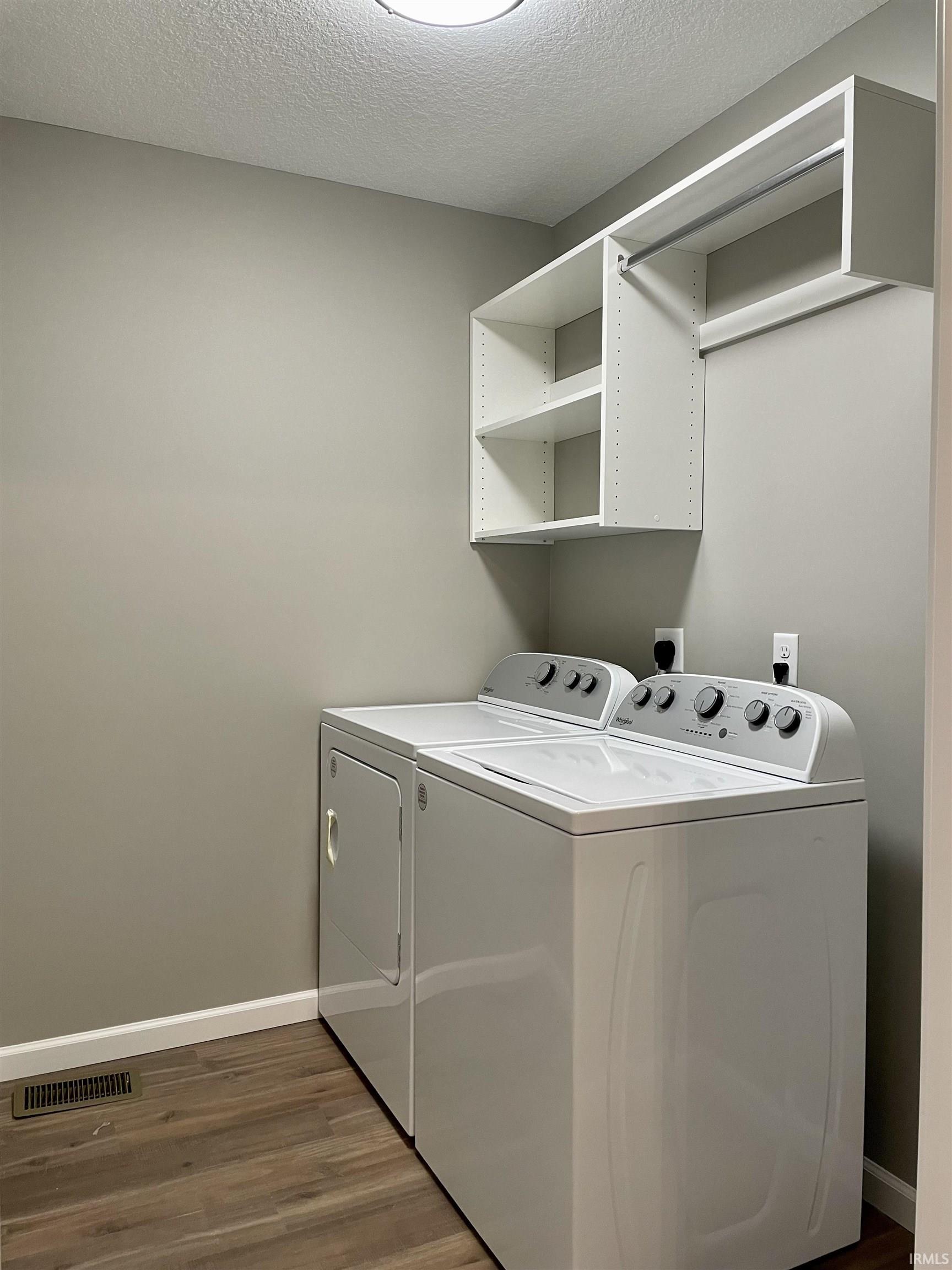 Laundry room featuring dark wood-style floors, a textured ceiling, and washer and clothes dryer