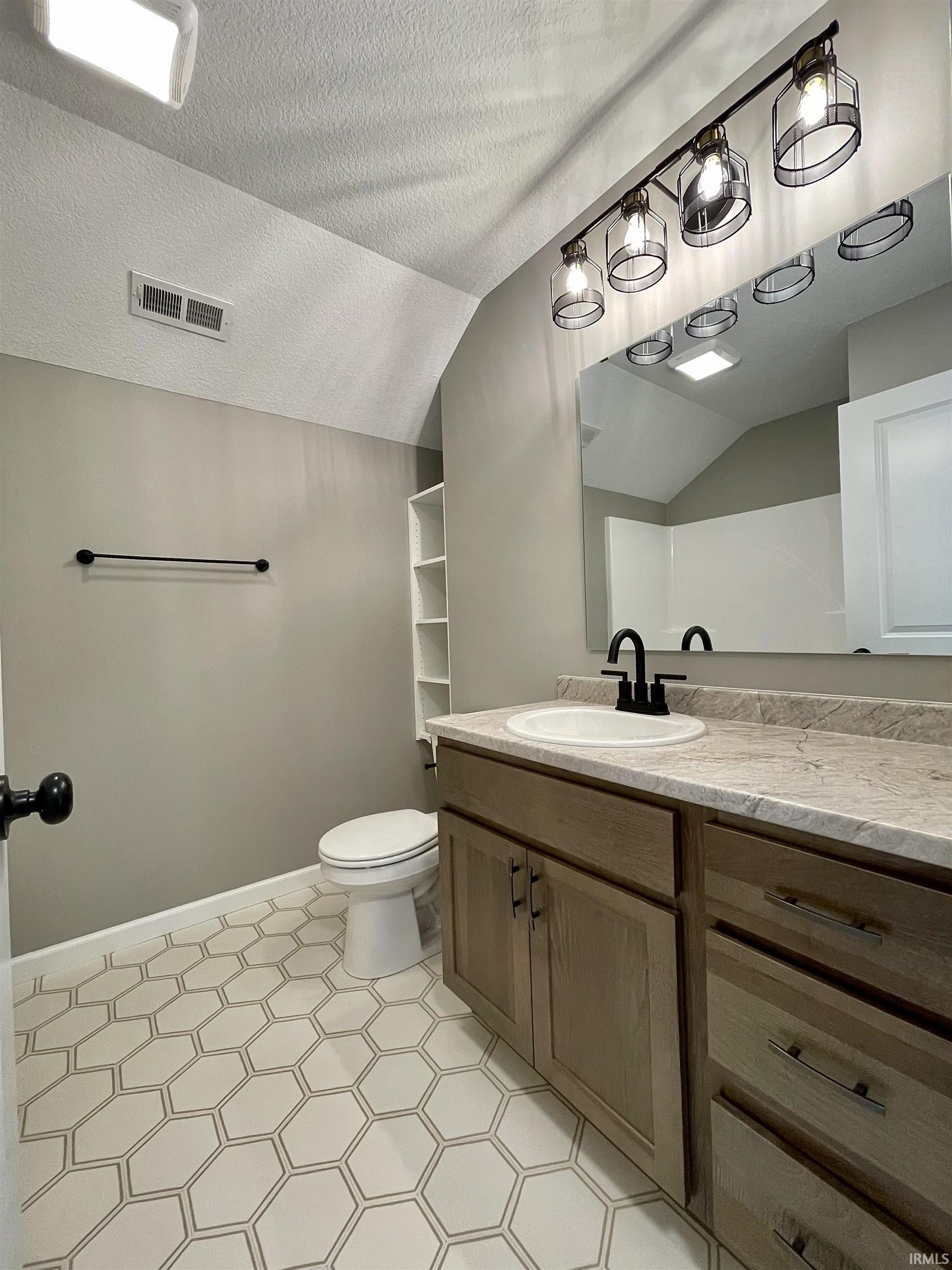 Full bathroom with lofted ceiling, a textured ceiling, and vanity