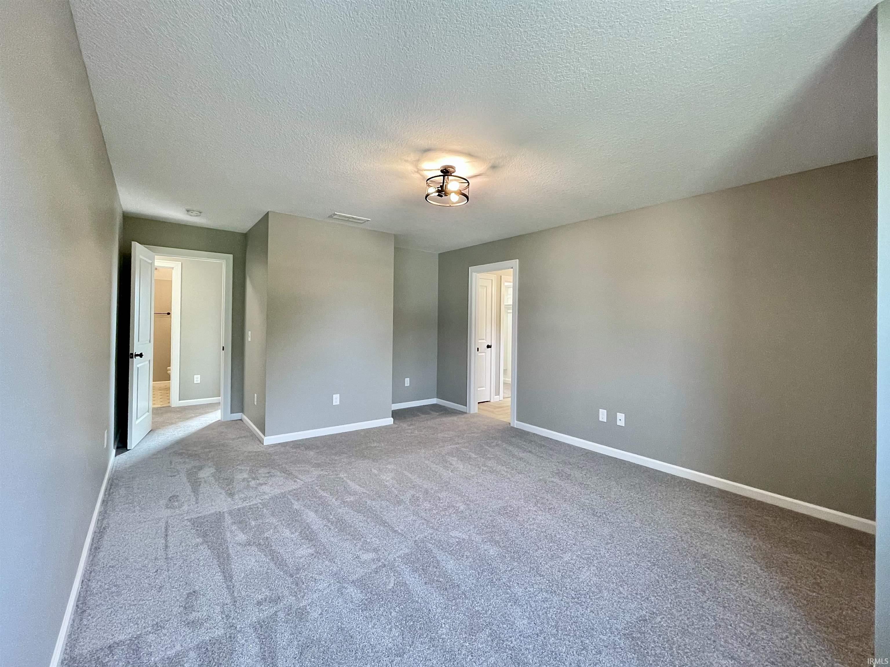 Unfurnished bedroom with light colored carpet and a textured ceiling
