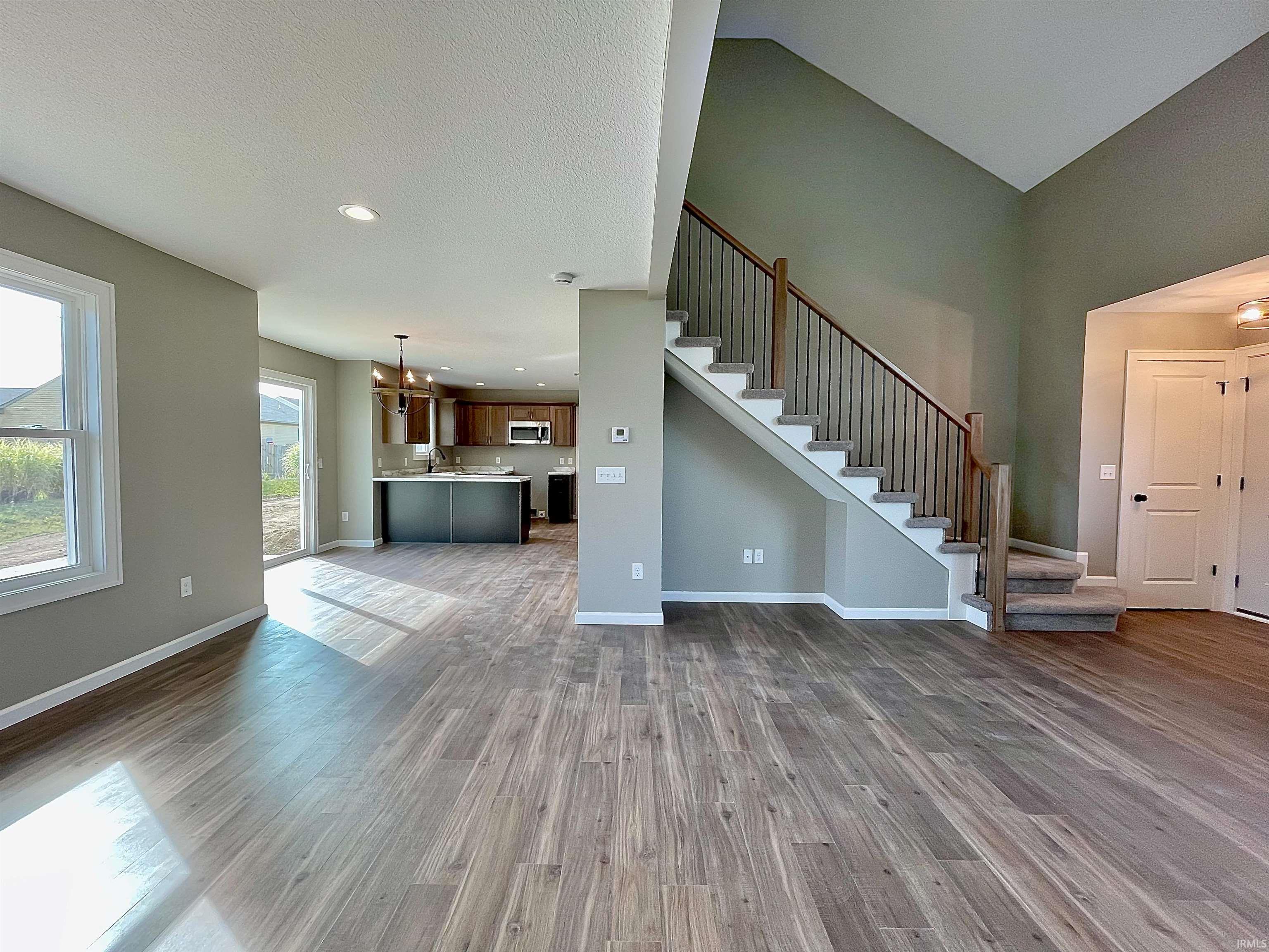 Unfurnished living room featuring stairs, recessed lighting, dark wood finished floors, and a chandelier