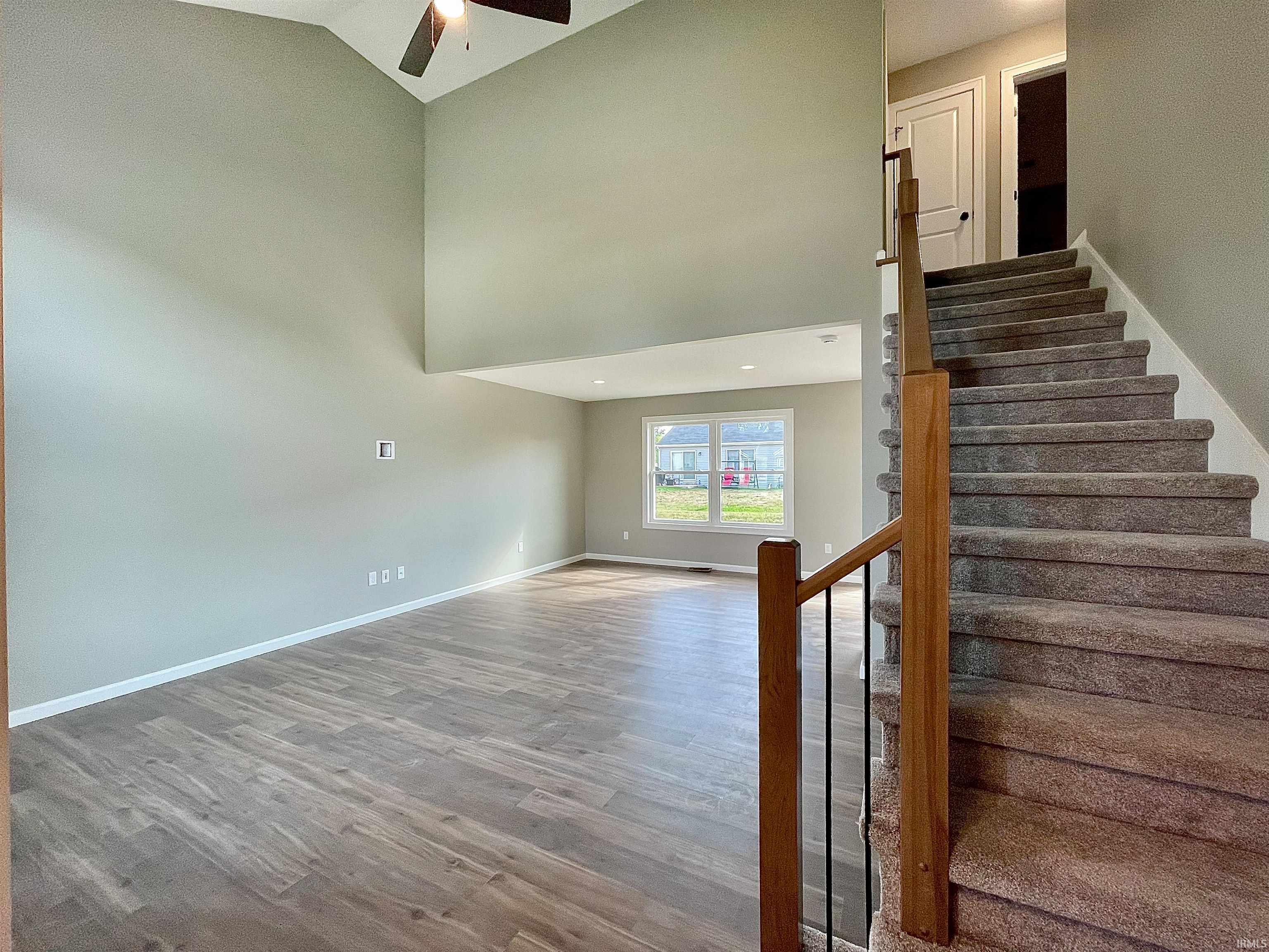 Stairway featuring a towering ceiling, wood finished floors, and ceiling fan