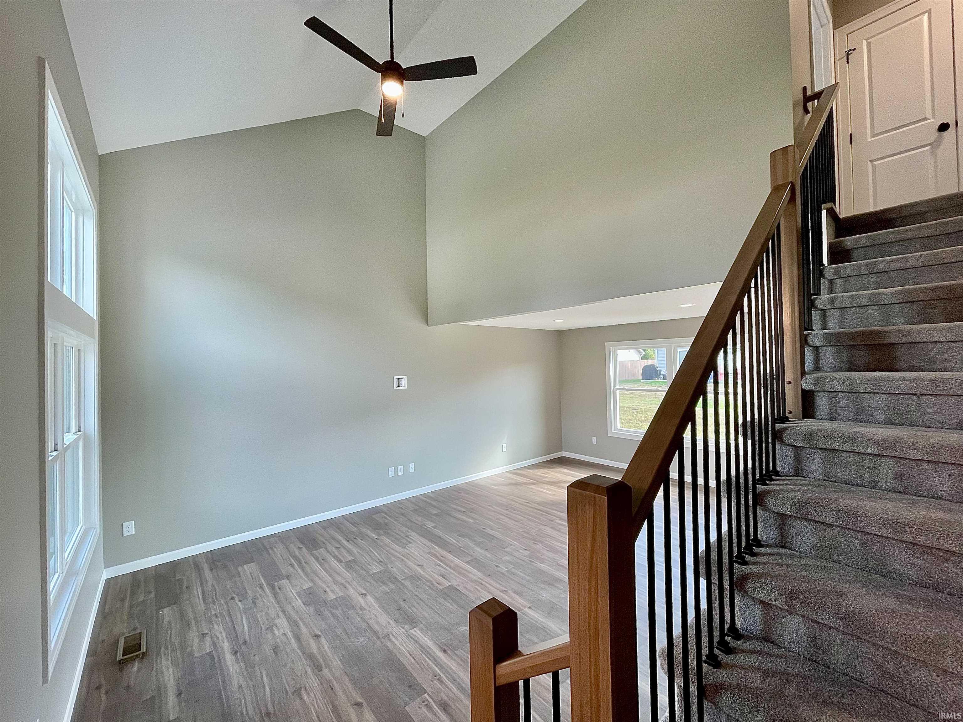 Staircase featuring wood finished floors, ceiling fan, and a high ceiling