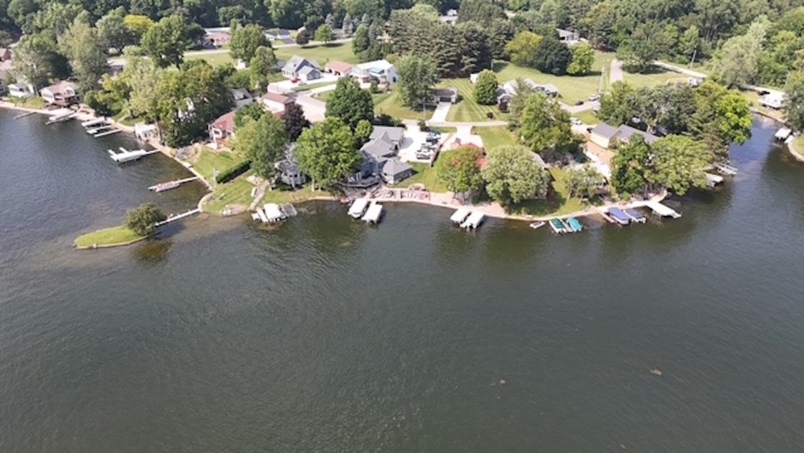 Aerial view of property and surrounding area featuring a large body of water and a tree filled landscape