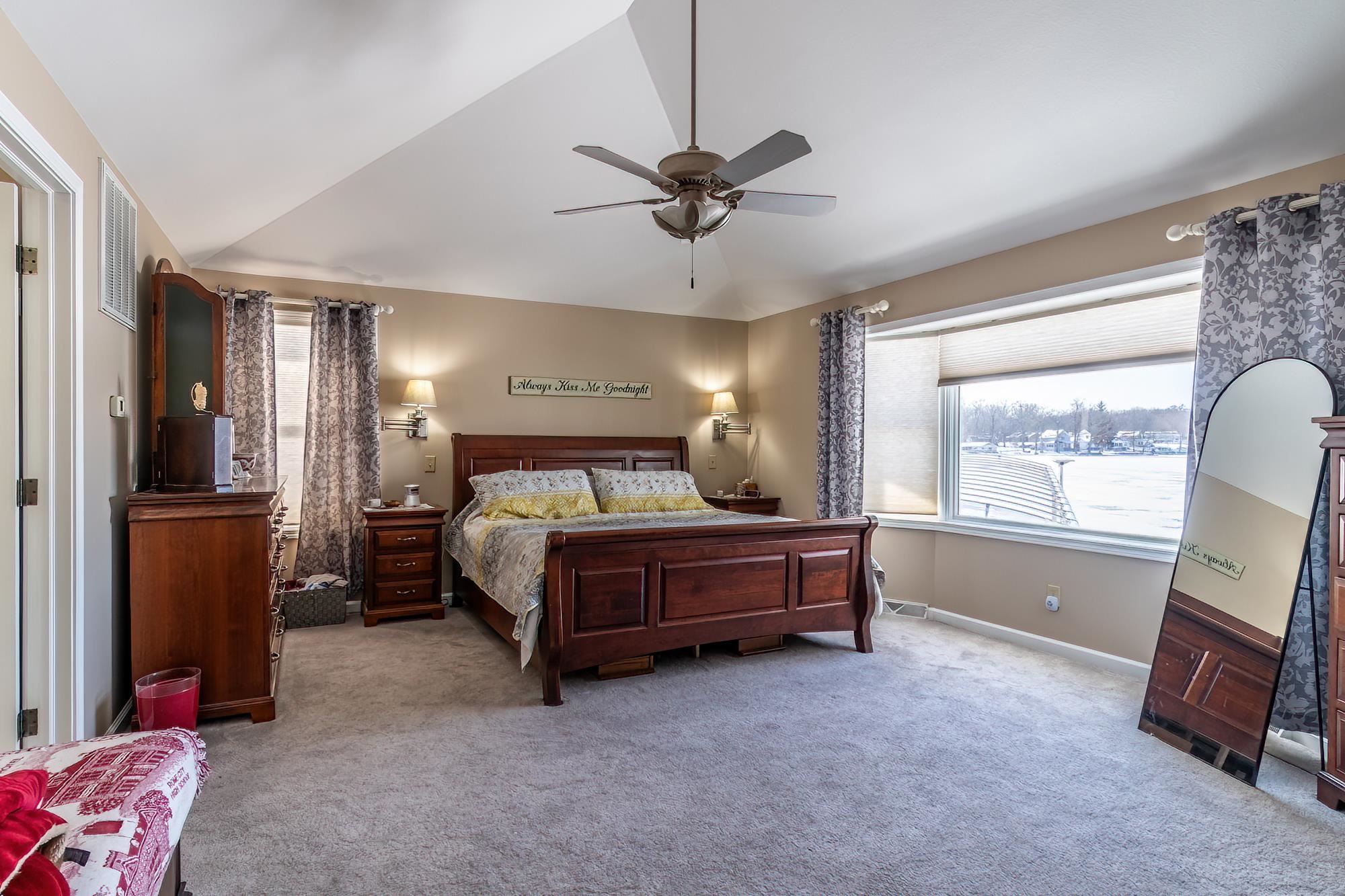 Bedroom featuring carpet, multiple windows, and a ceiling fan