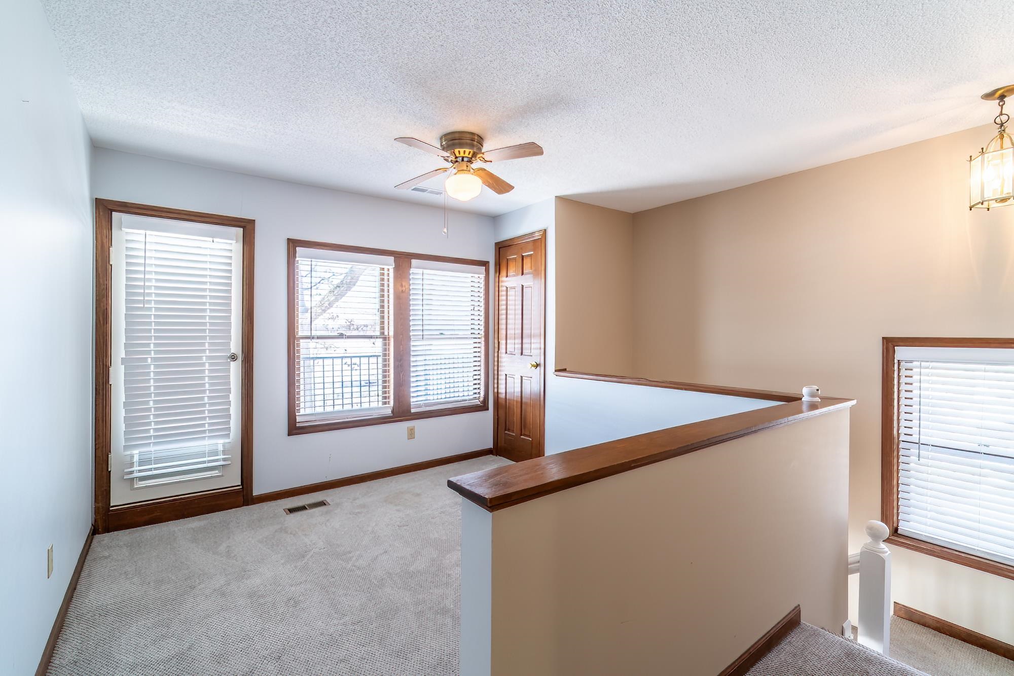 Interior space featuring an upstairs landing, light colored carpet, and a textured ceiling