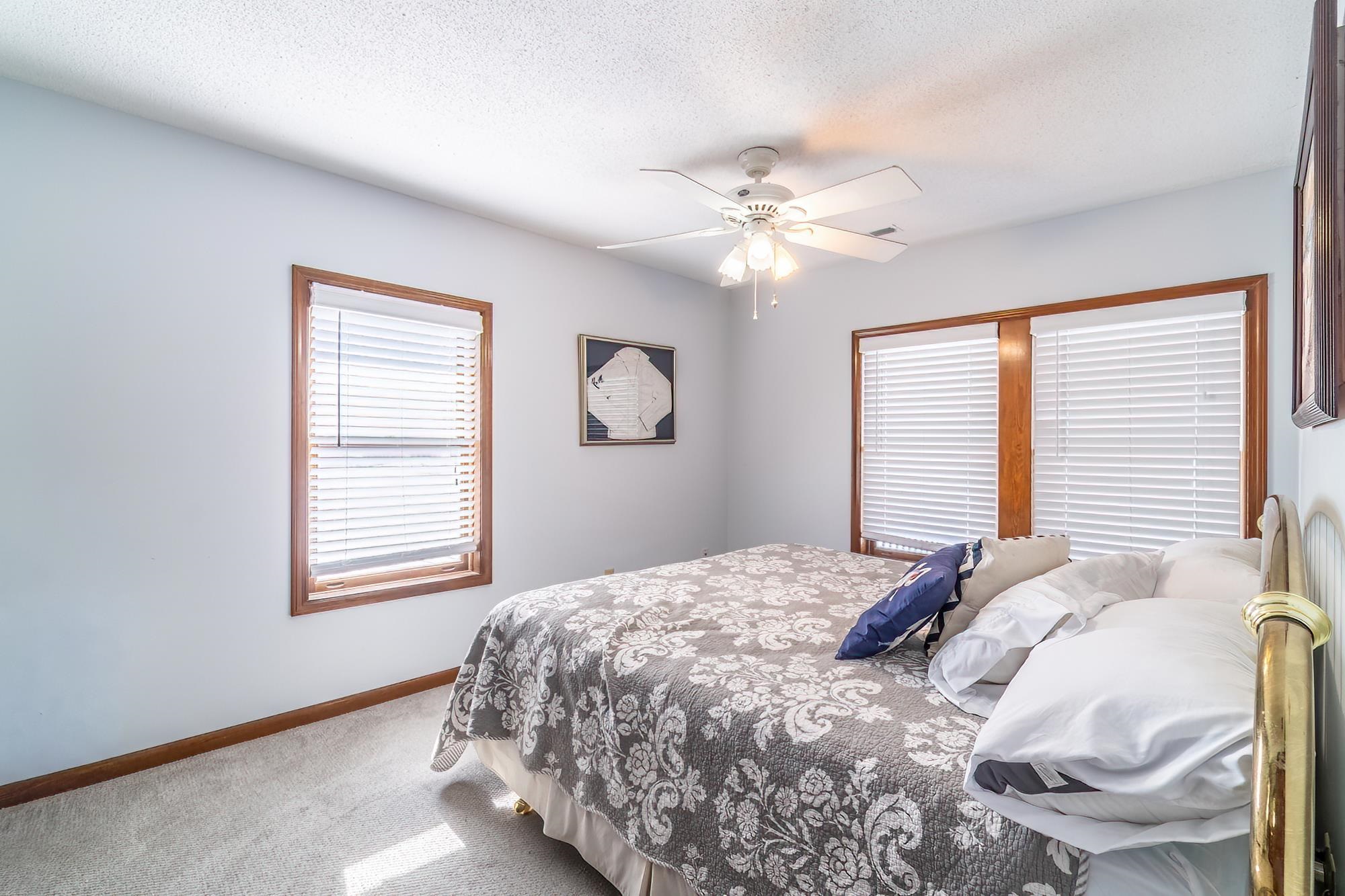 Carpeted bedroom featuring ceiling fan and a textured ceiling
