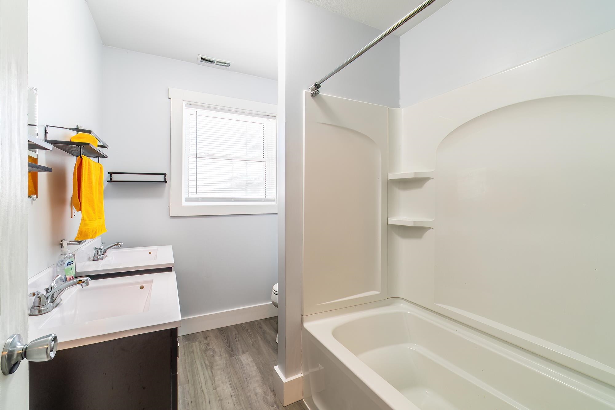 Full bathroom with vanity, light wood-type flooring, and tub / shower combination