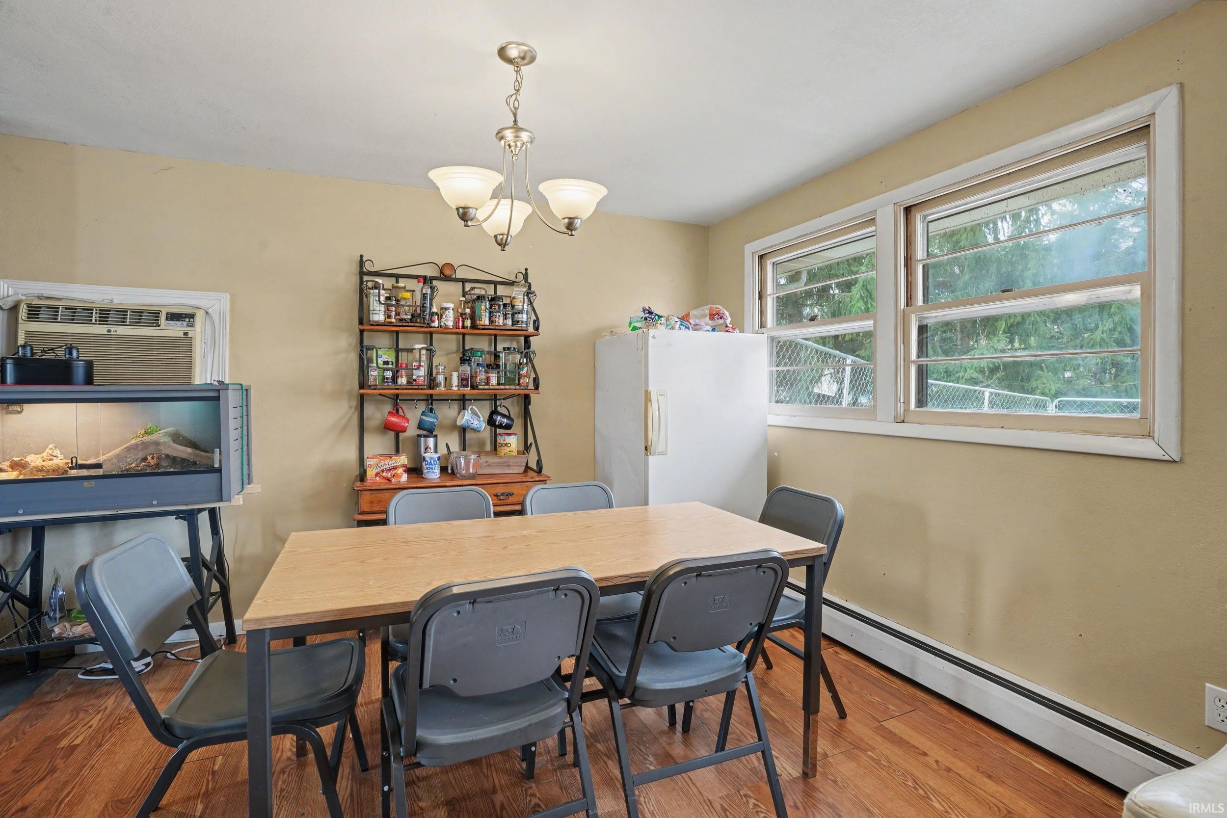 Dining area with a baseboard radiator, light wood-type flooring, and suspended lighting