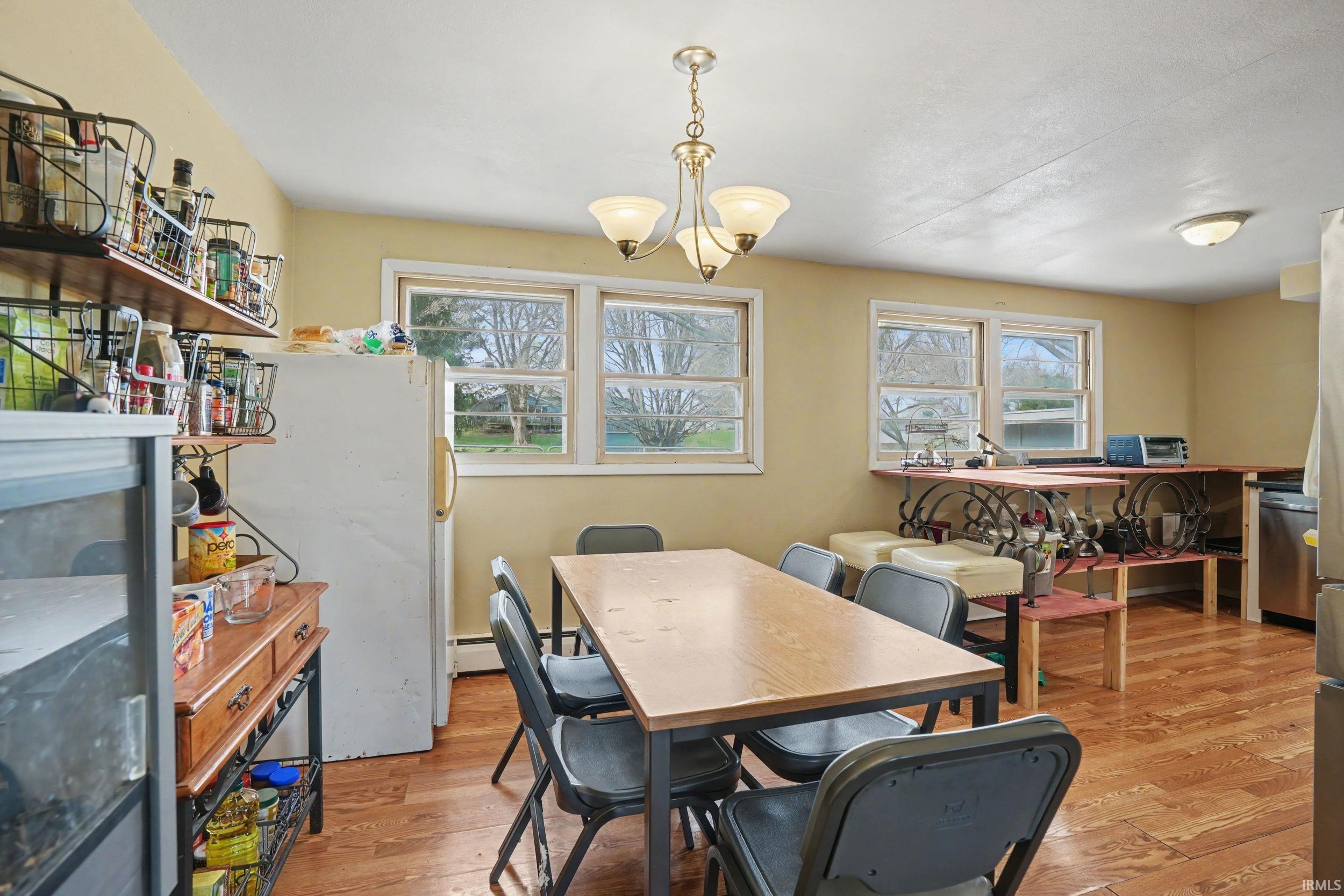 Dining room featuring light wood finished floors, hanging lights, and a baseboard radiator