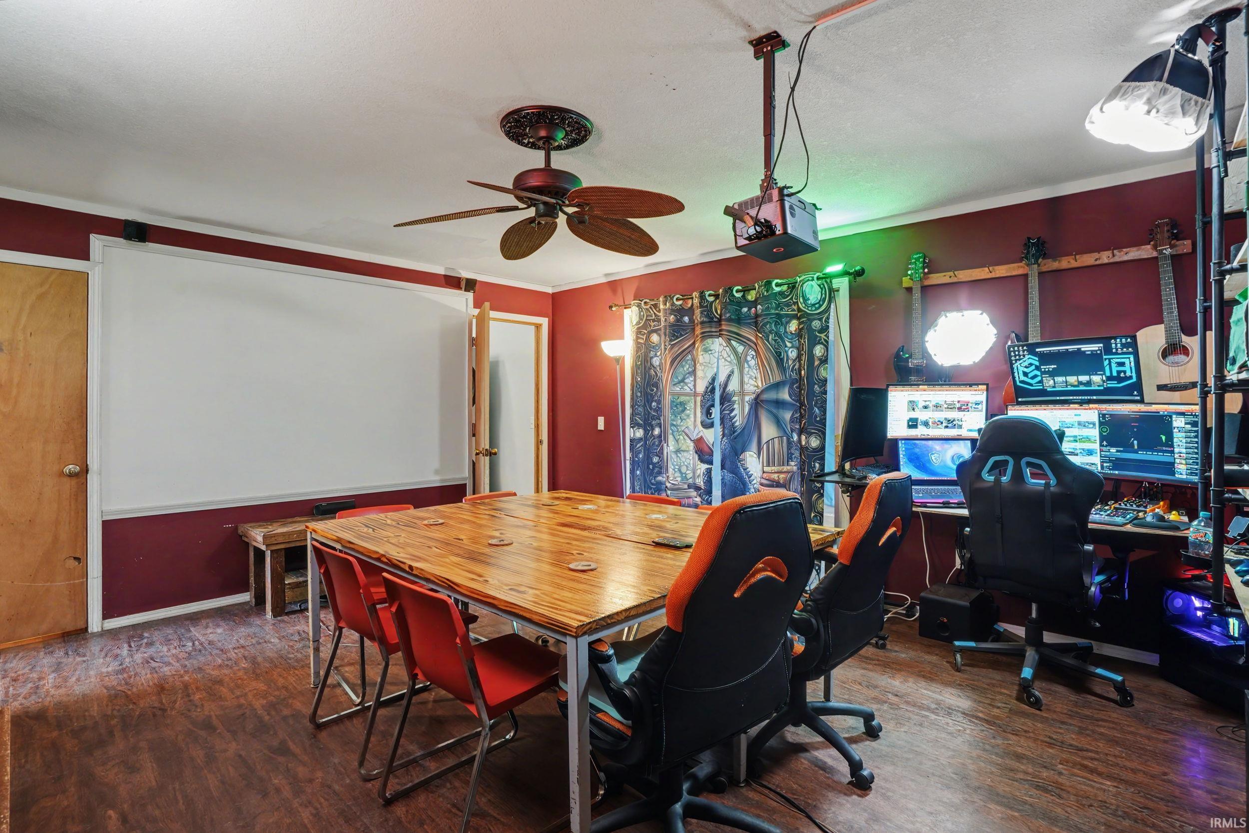 Family area with dark wood finished floors, a ceiling fan, and crown molding