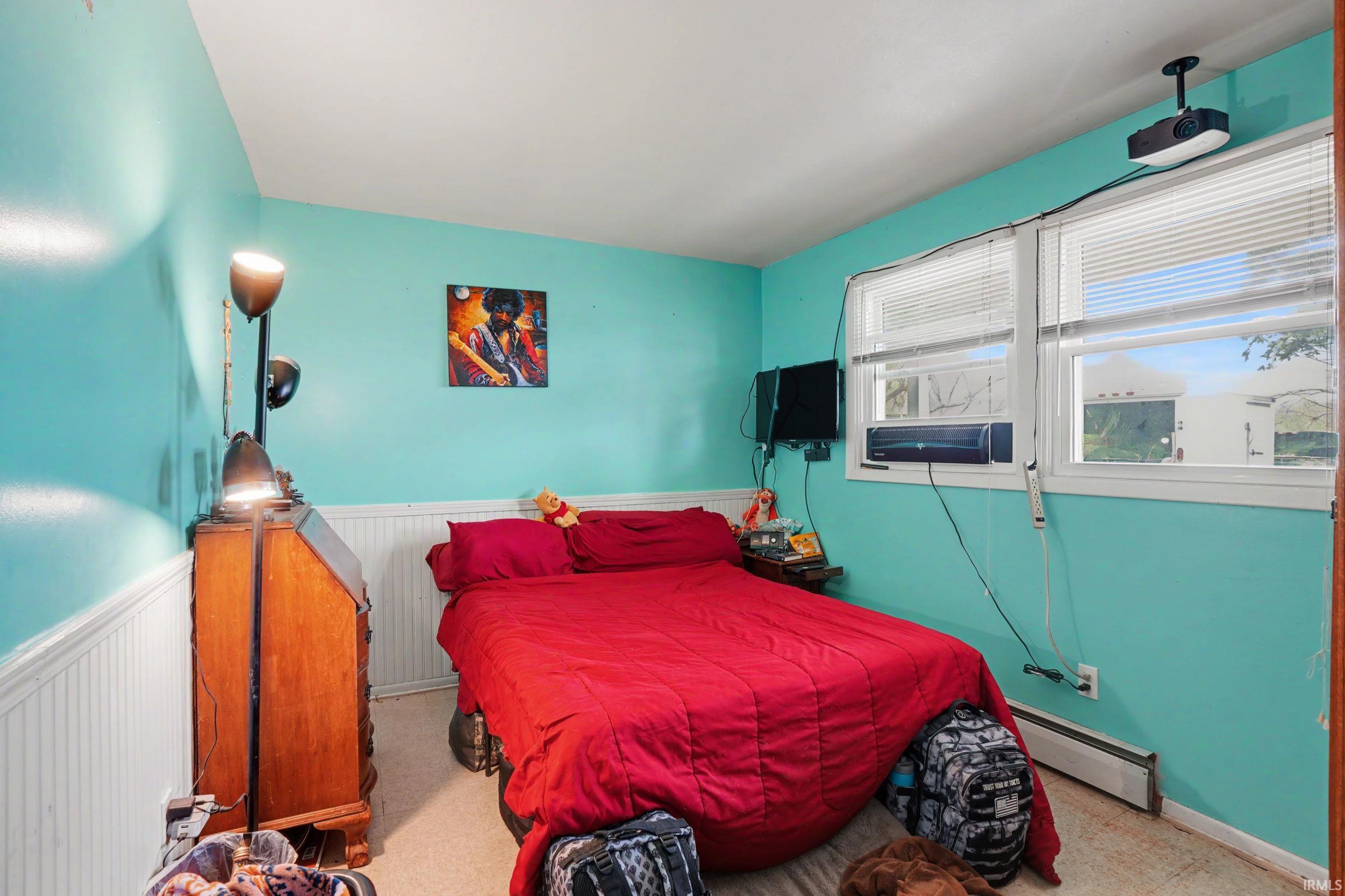 Bedroom featuring baseboard heating and wainscoting