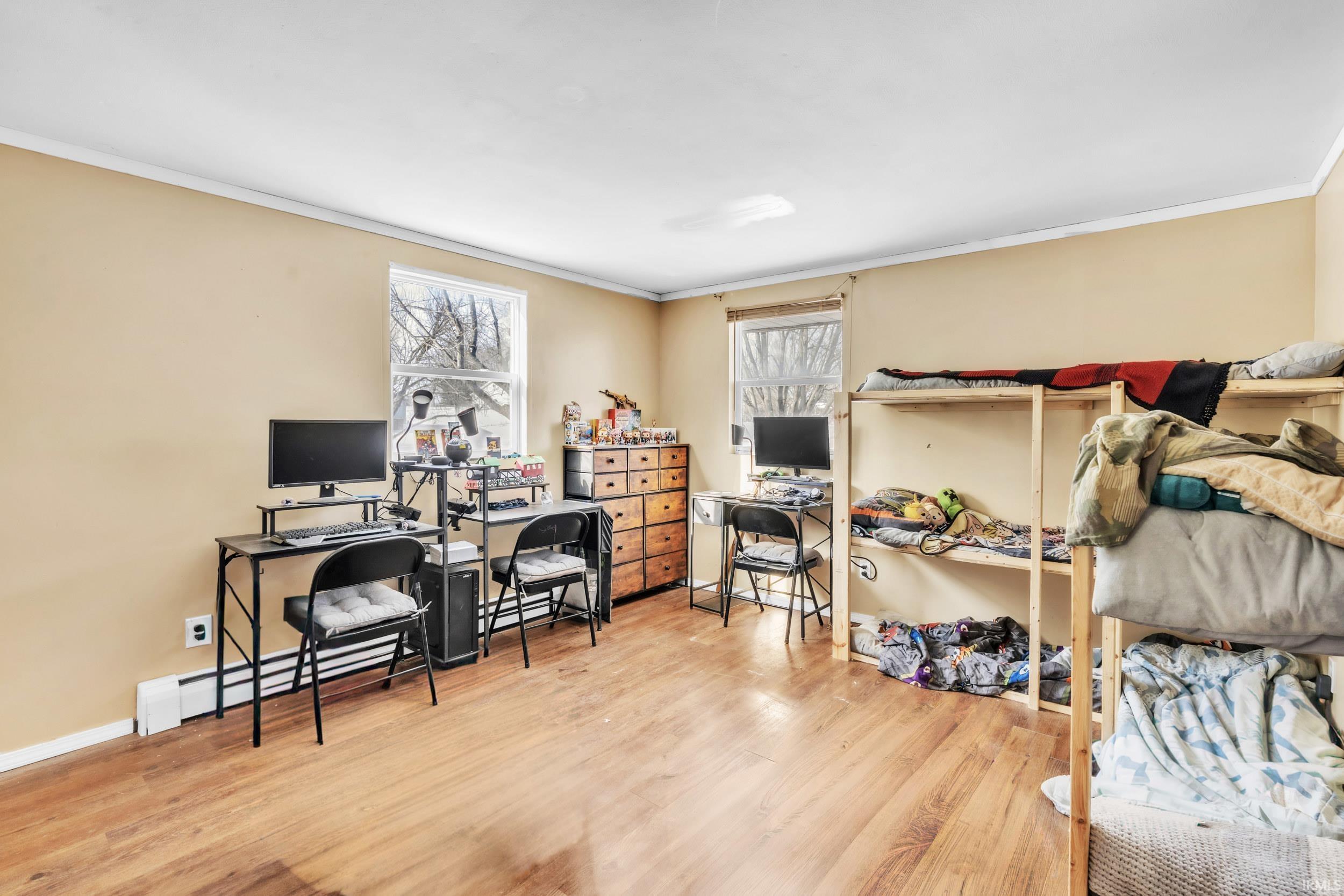 Office with crown molding, light wood-type flooring, and a baseboard heating unit