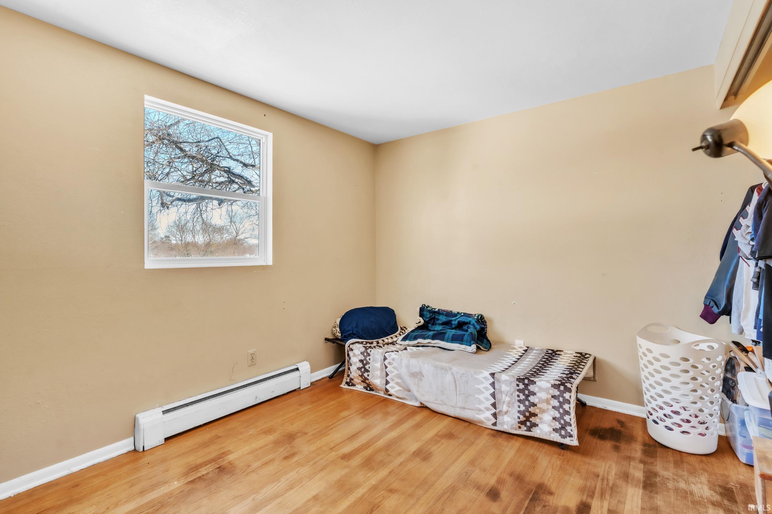 Sitting room featuring a baseboard heating unit and wood finished floors