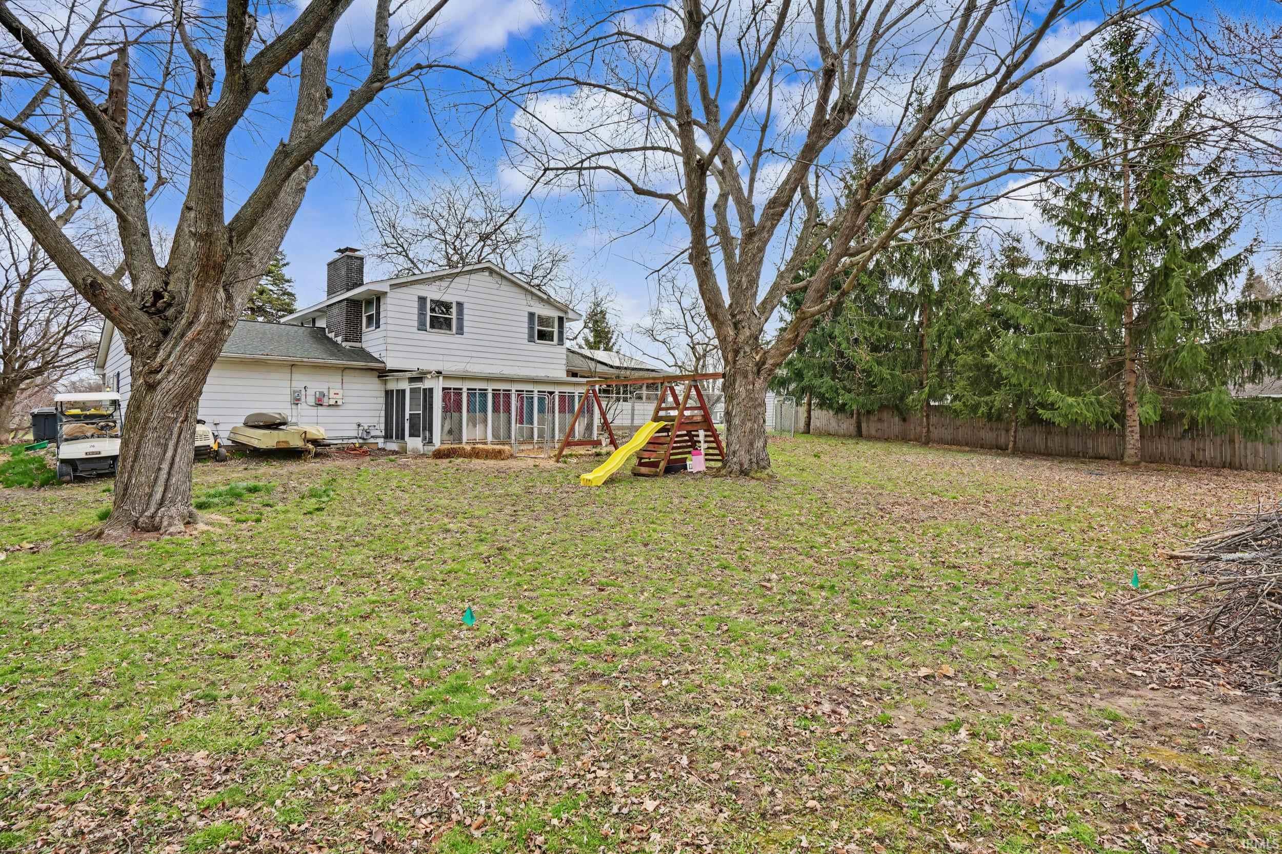 Back of property featuring a playground, a chimney, and a fenced backyard