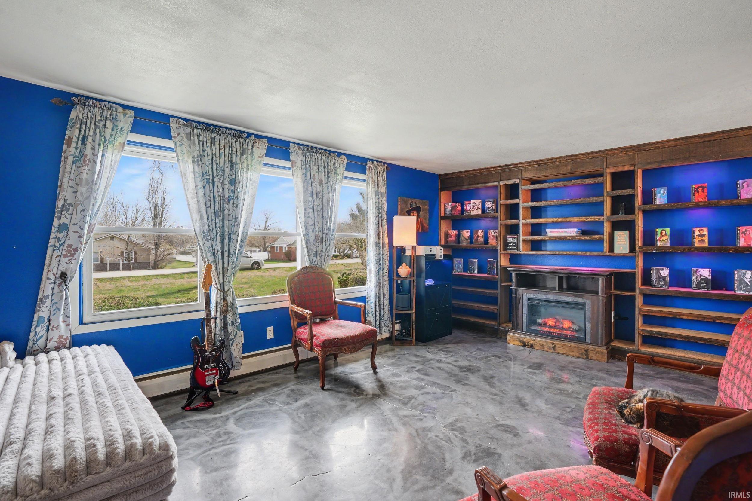 Sitting room with a glass covered fireplace, finished concrete floors, baseboard heating, and a textured ceiling