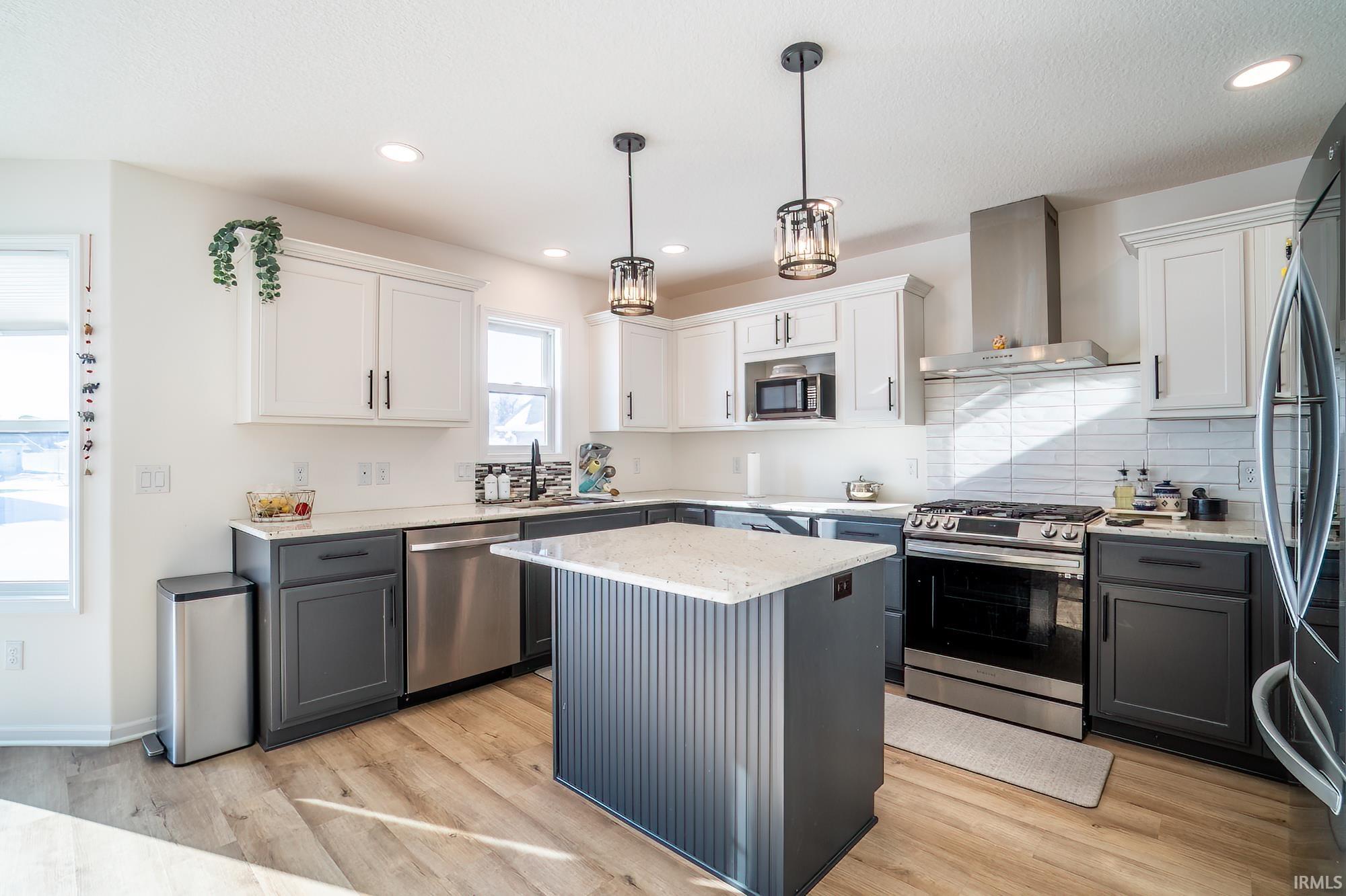Kitchen with gray cabinets, appliances with stainless steel finishes, wall chimney range hood, white cabinetry, and recessed lighting