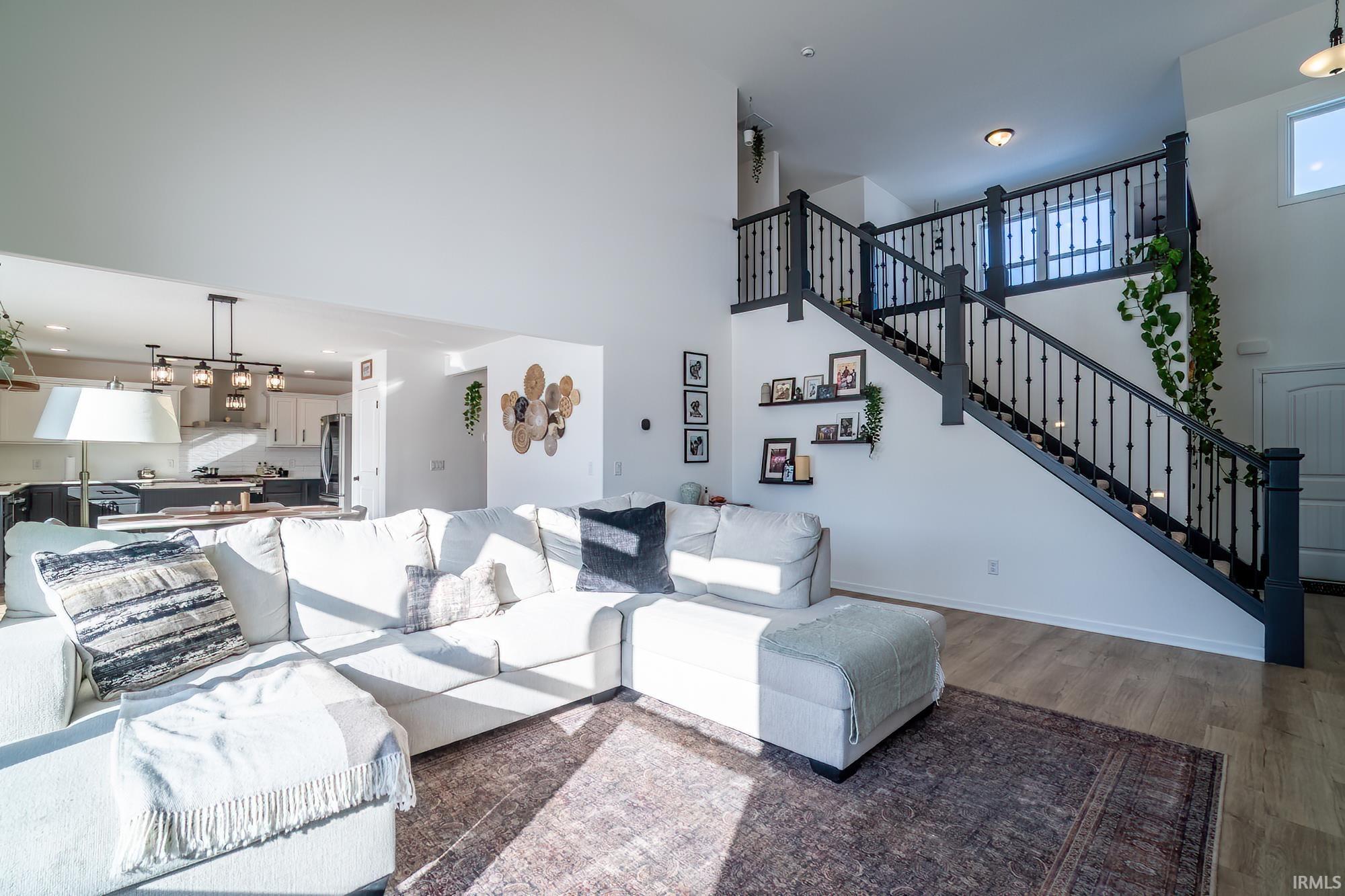 Living area featuring stairway, a high ceiling, wood finished floors, and recessed lighting