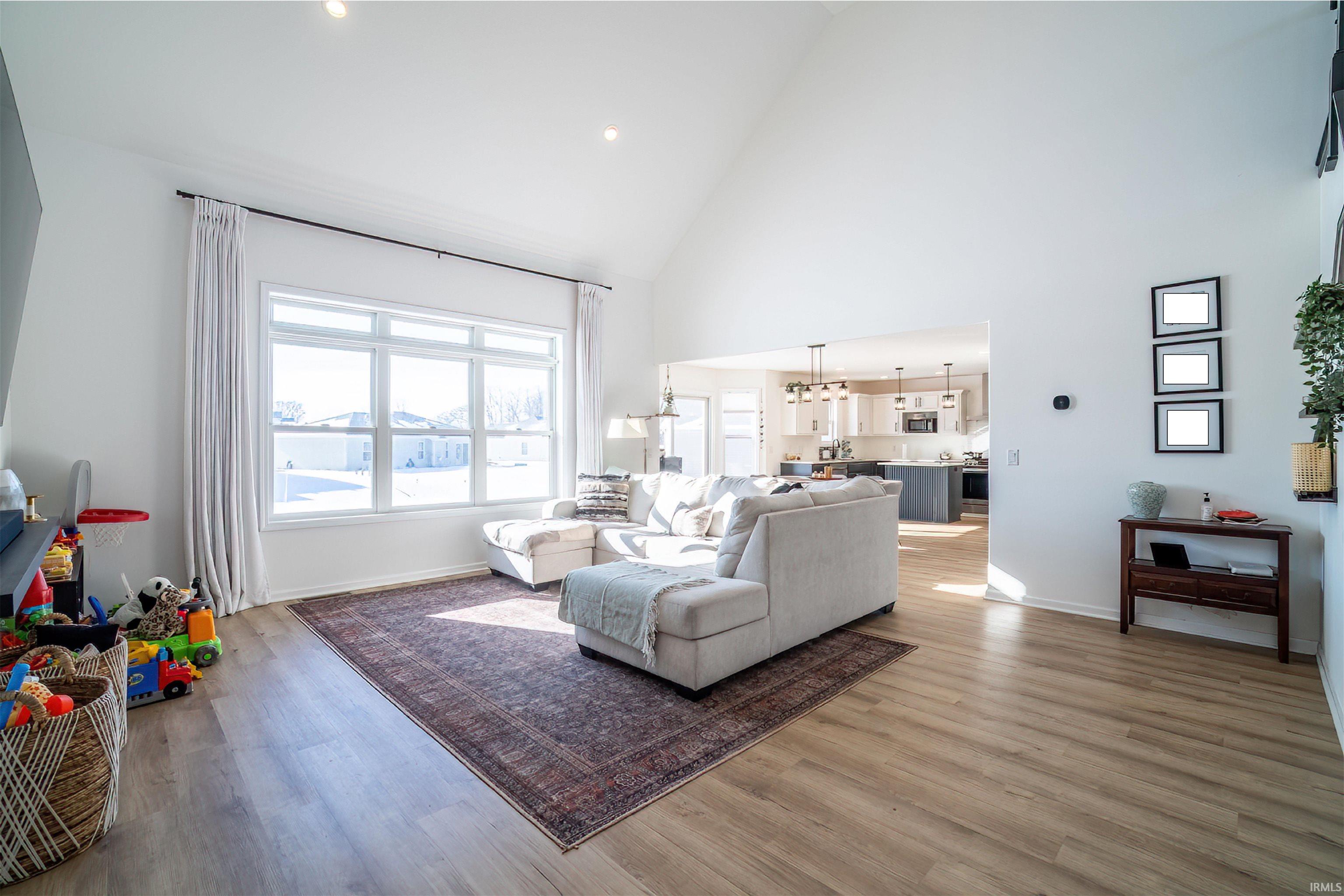 Living area featuring light wood-style floors, recessed lighting, high vaulted ceiling, and a chandelier