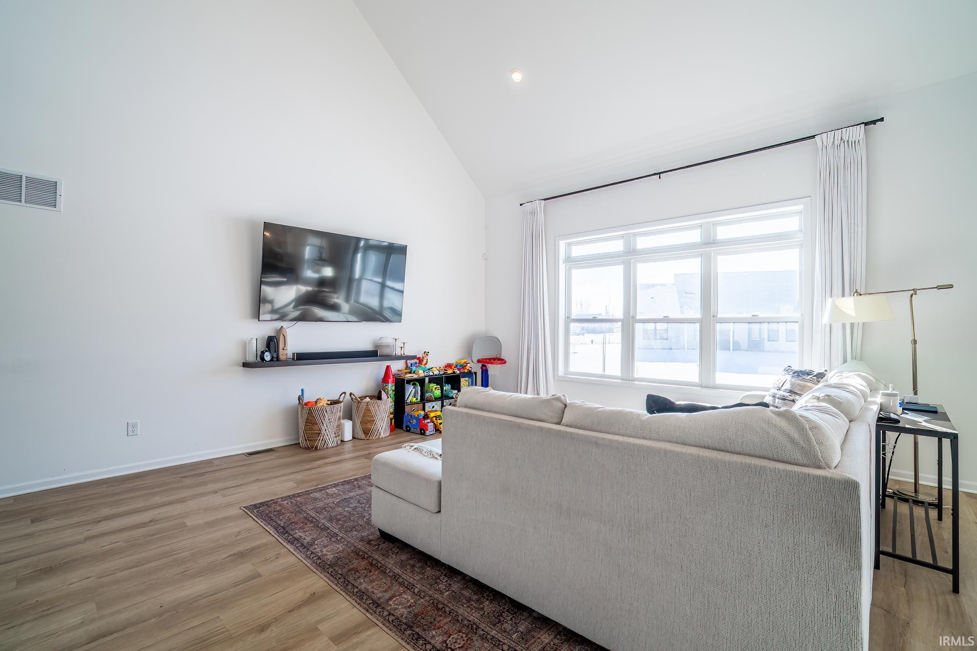 Living area with high vaulted ceiling, light wood finished floors, and recessed lighting