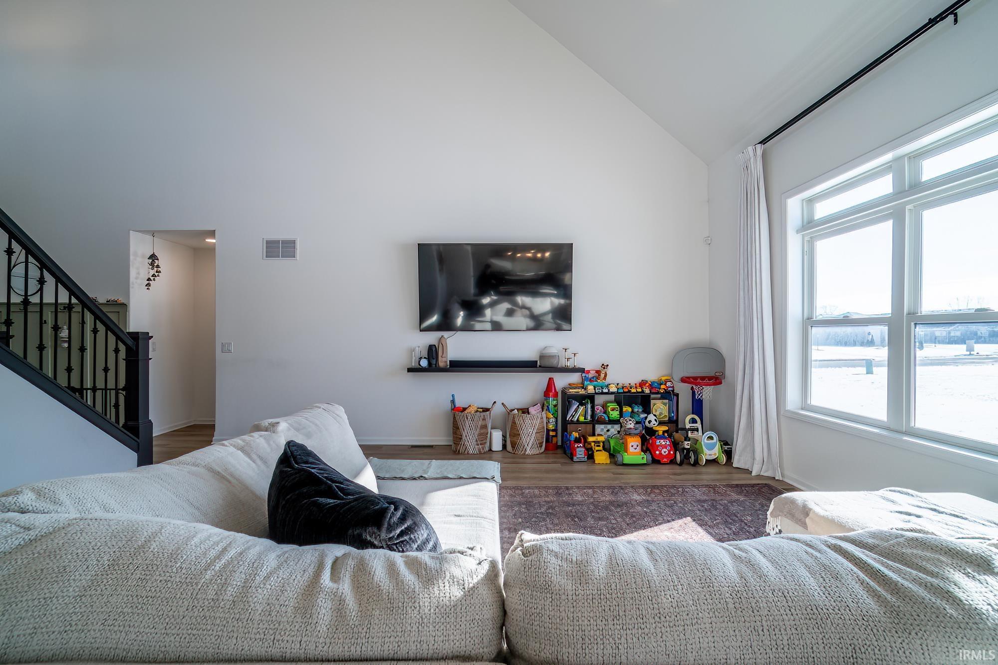 Living room featuring stairway, wood finished floors, and high vaulted ceiling