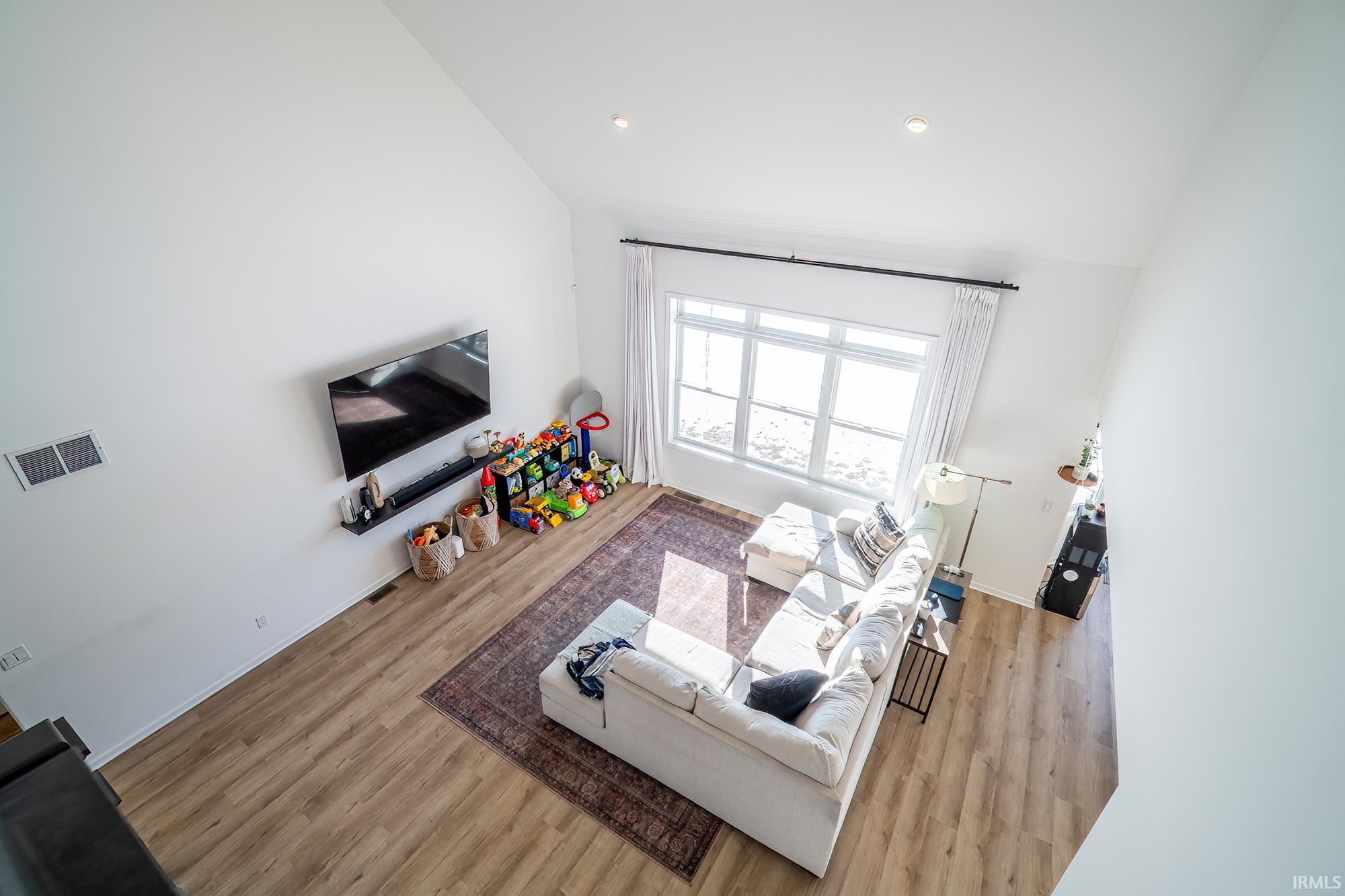 Living room with light wood-style flooring, high vaulted ceiling, and recessed lighting