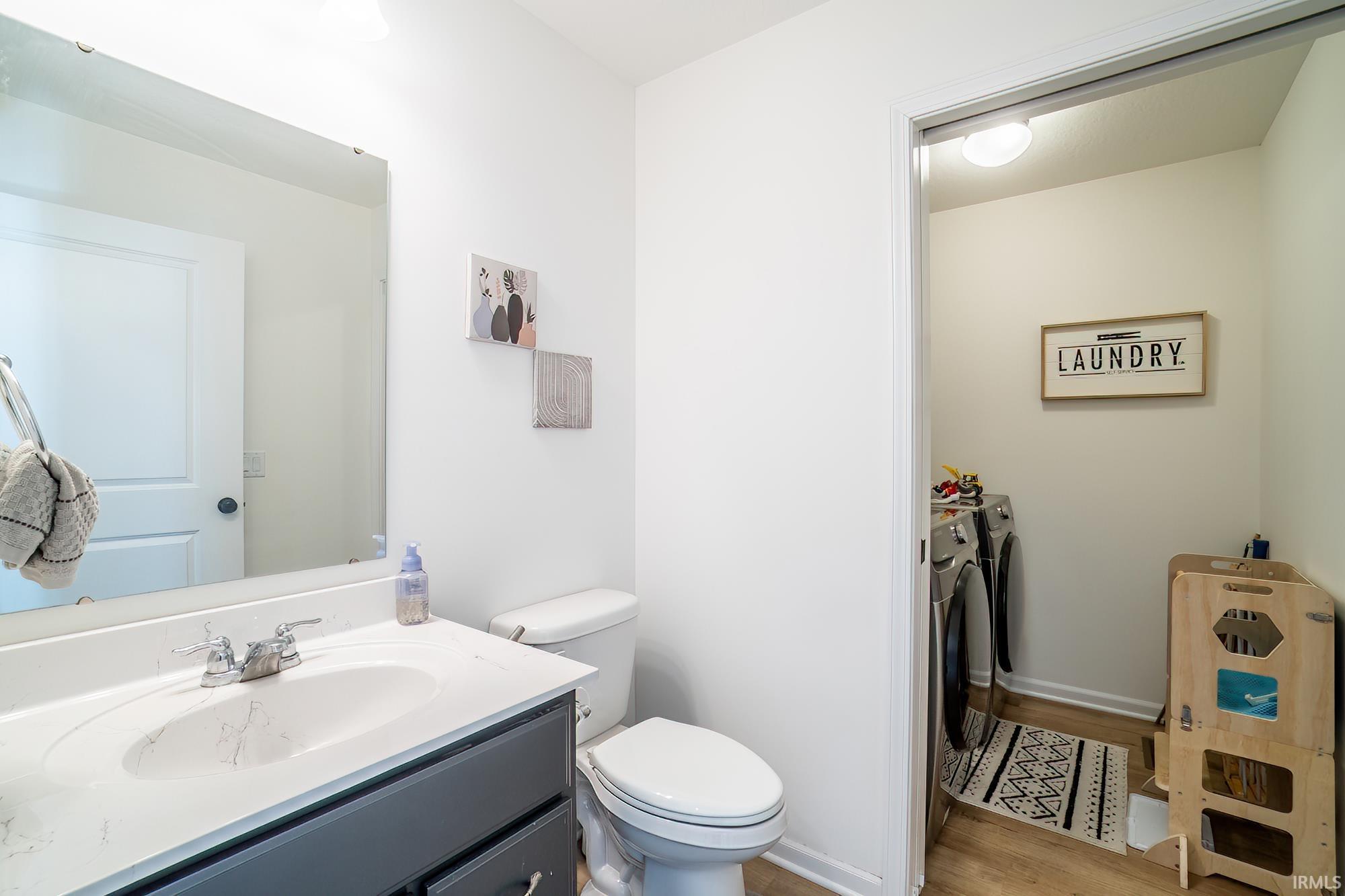 Bathroom featuring independent washer and dryer, vanity, and light wood-style floors