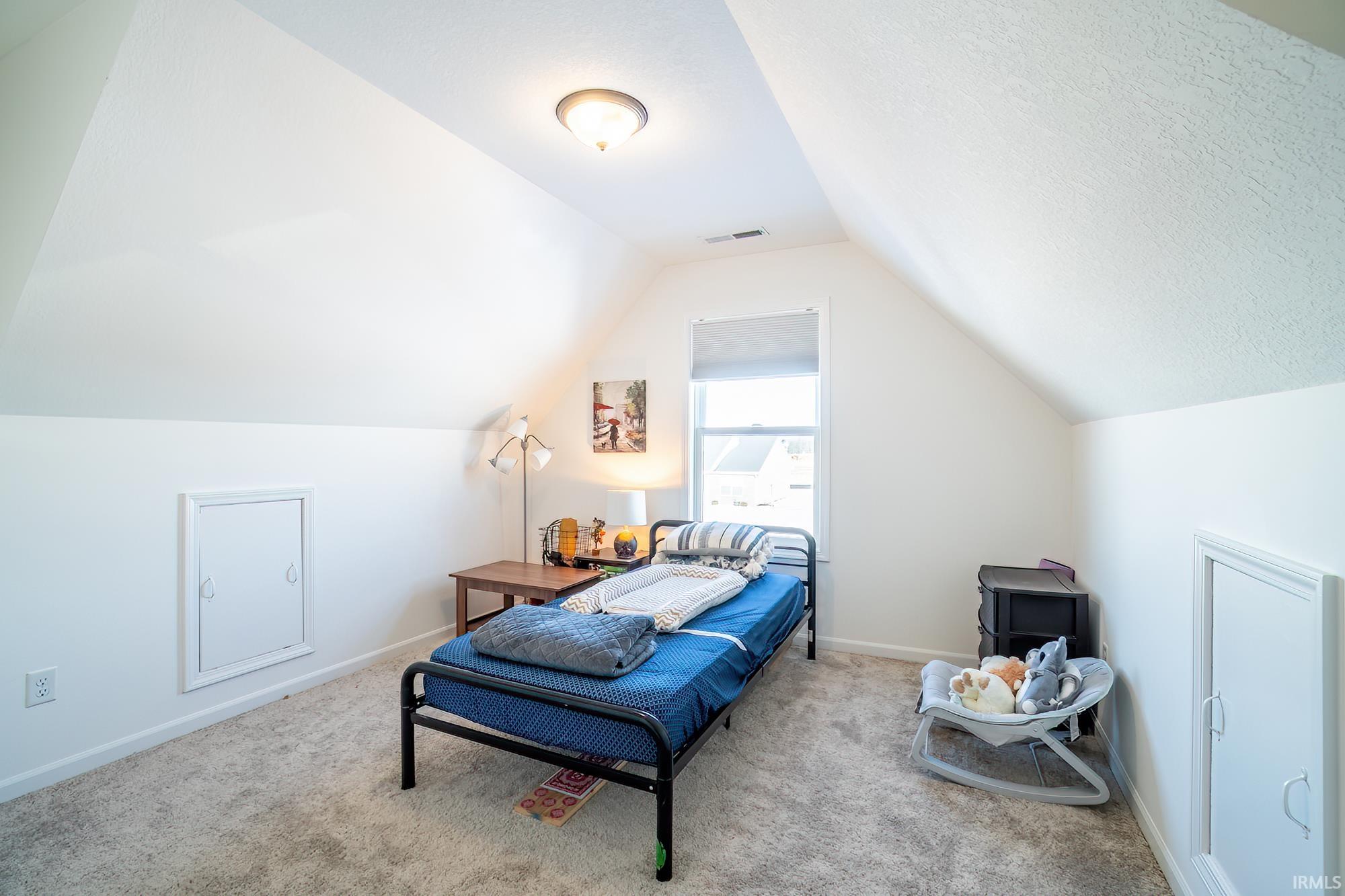 Carpeted bedroom with baseboards and vaulted ceiling