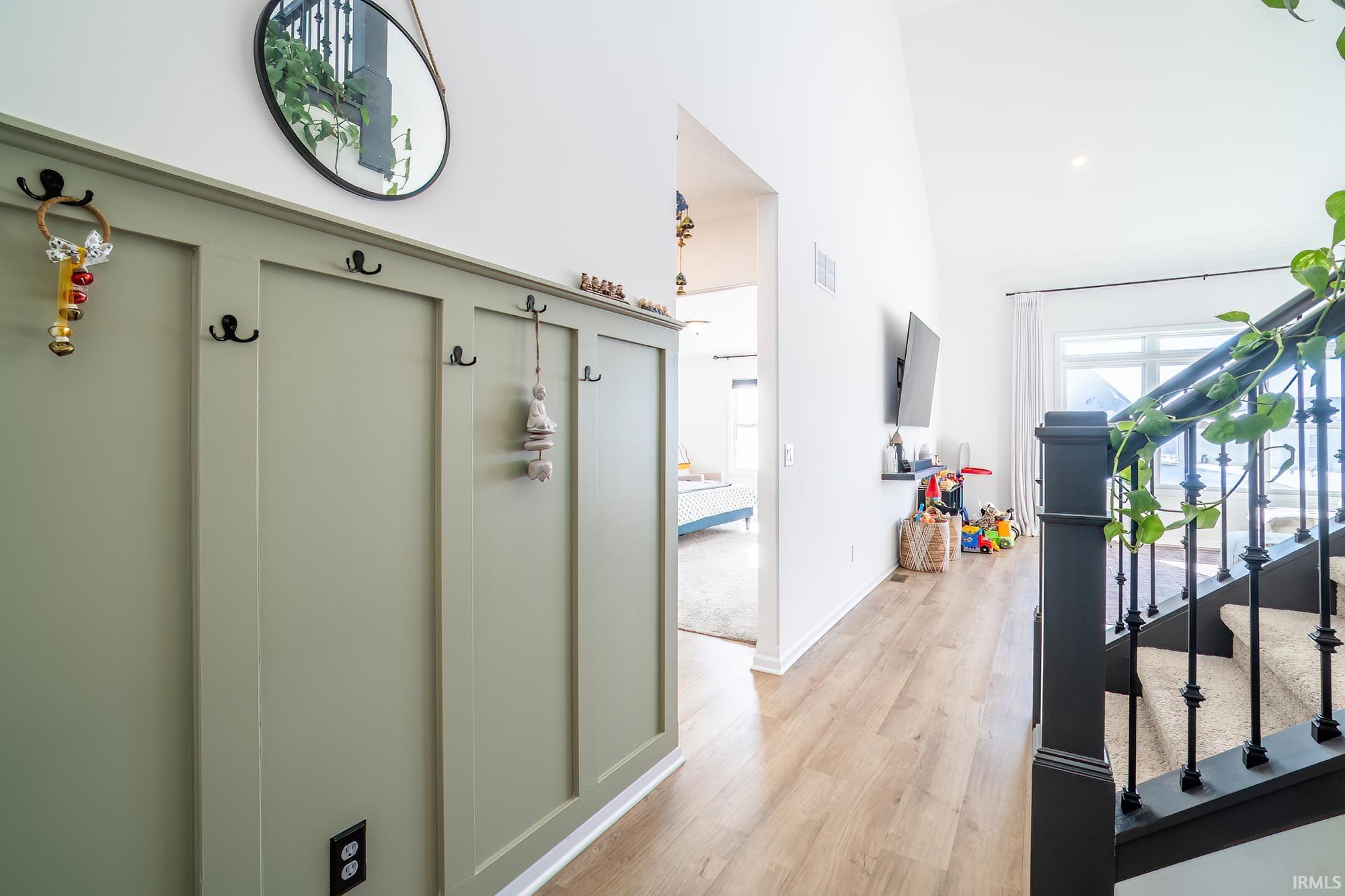 Corridor featuring stairs, a high ceiling, and light wood-type flooring
