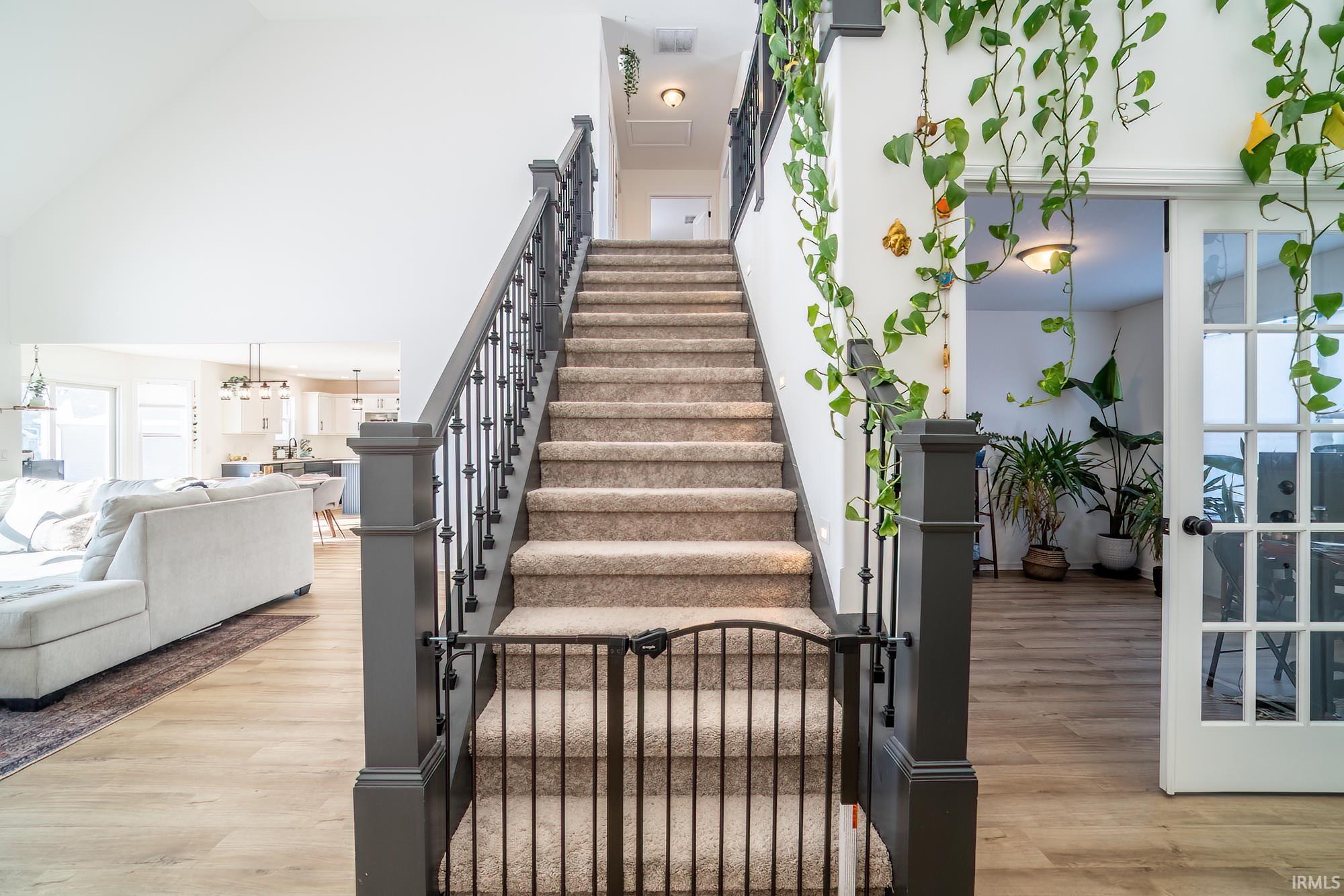 Staircase featuring wood finished floors, a towering ceiling, and a chandelier