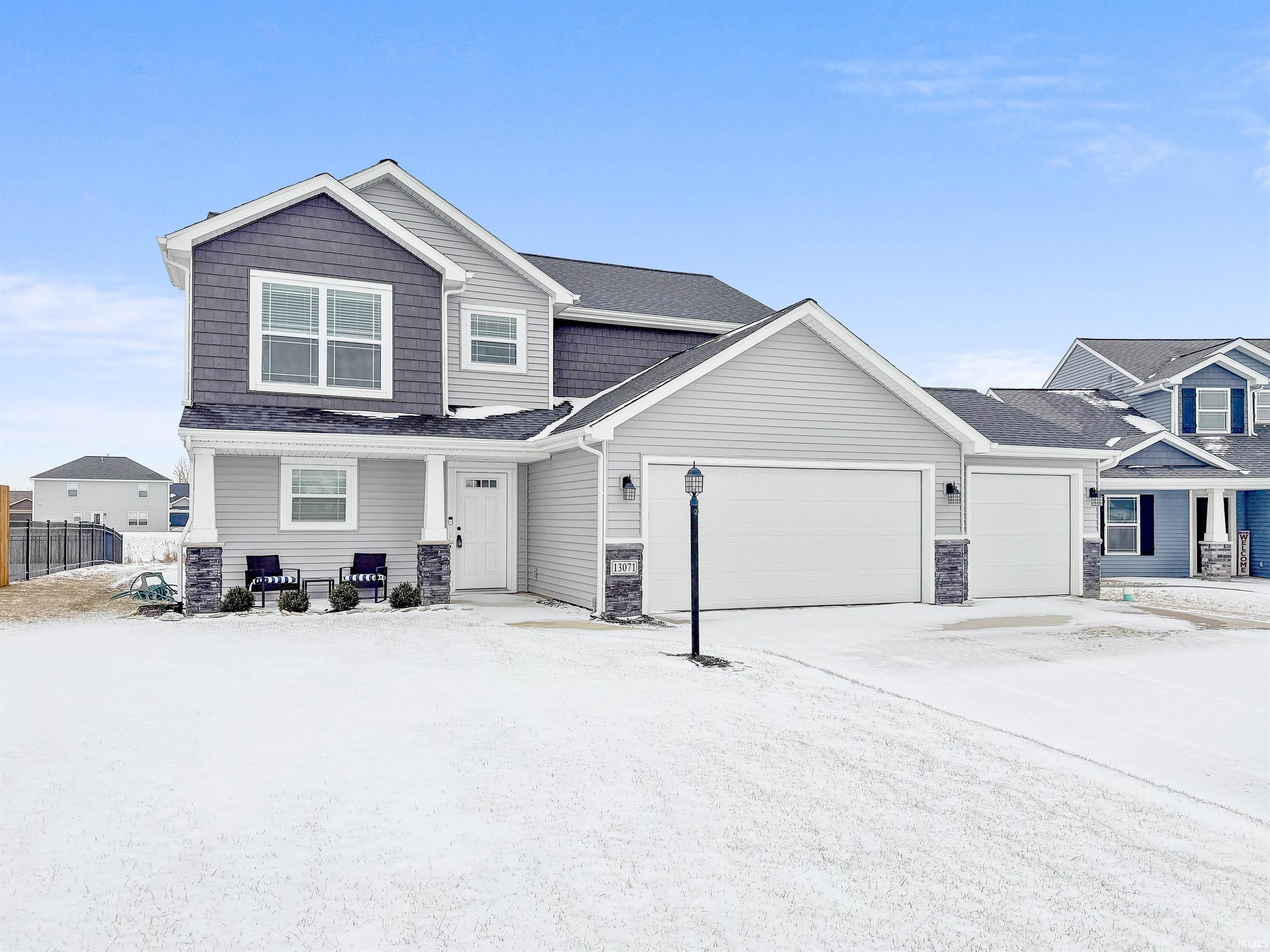 Craftsman-style house featuring an attached garage, driveway, stone siding, and roof with shingles