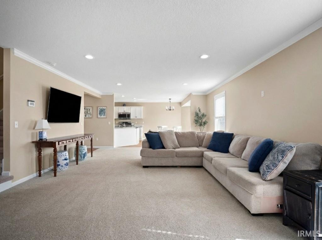 Living room featuring light carpet, recessed lighting, and ornamental molding