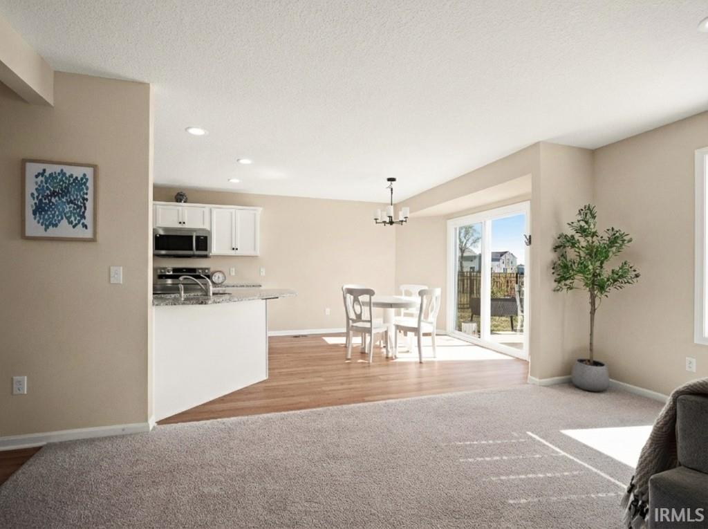 Living room featuring recessed lighting, light carpet, a chandelier, and a textured ceiling
