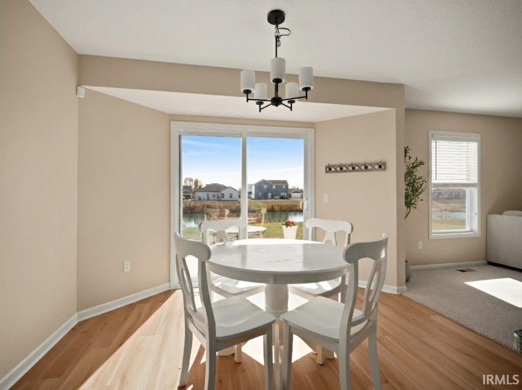 Dining area with plenty of natural light, wood finished floors, a chandelier, and a water view