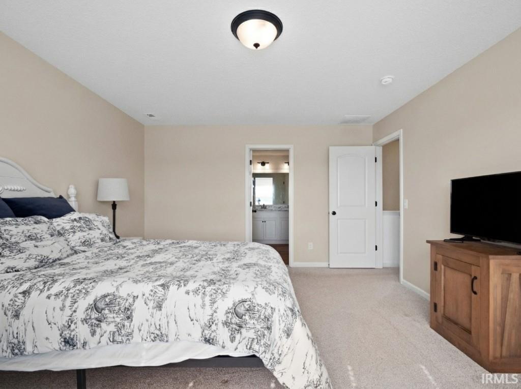 Bedroom with light carpet and connected bathroom